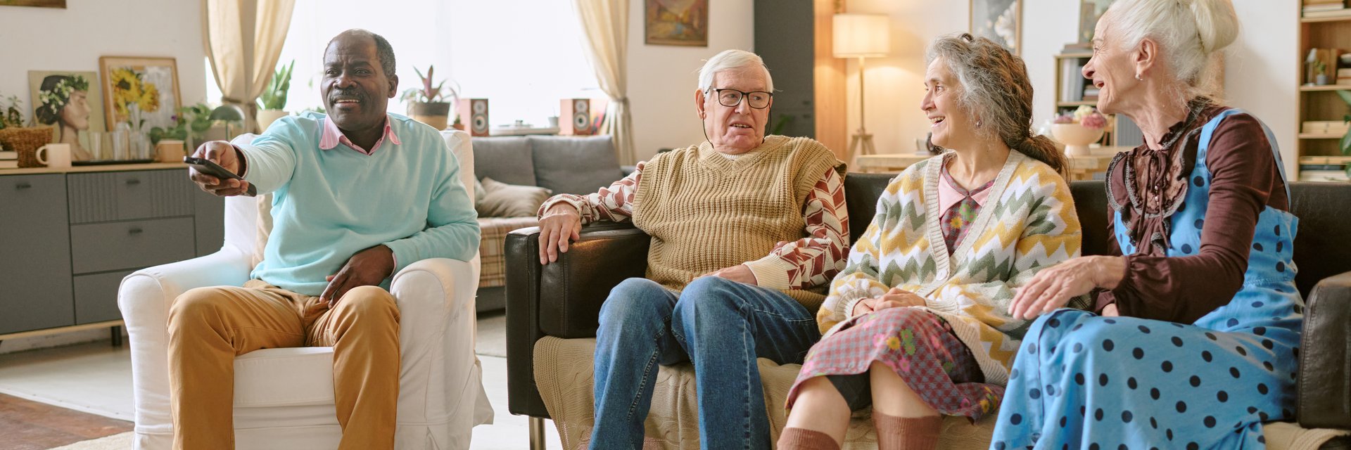Website banner with biracial residents of nursing home chilling in living room watching film and enjoying conversation