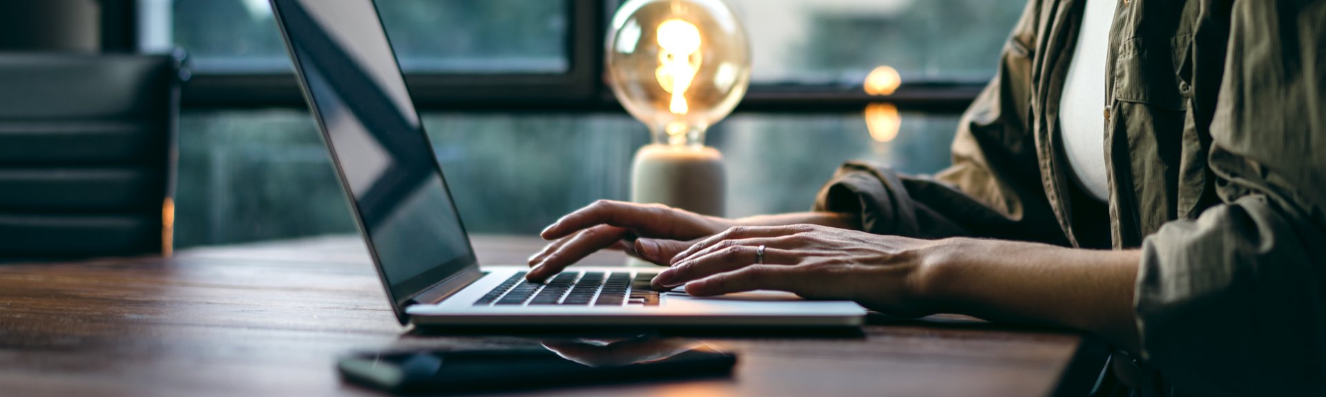 Young woman working with a laptop. Female freelancer connecting to internet via computer. Blogger or journalist writing new article. Close-up of female hands typing on keyboard