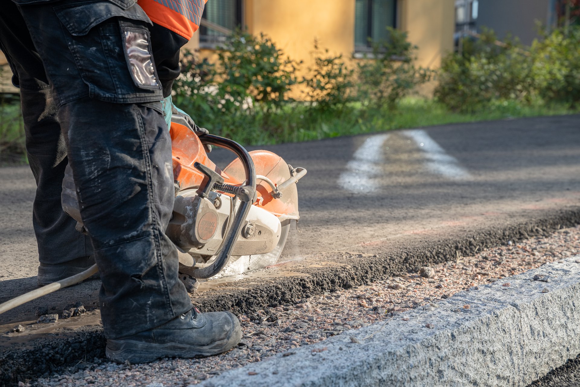 construction worker cuts the asphalt with a circular saw on a road