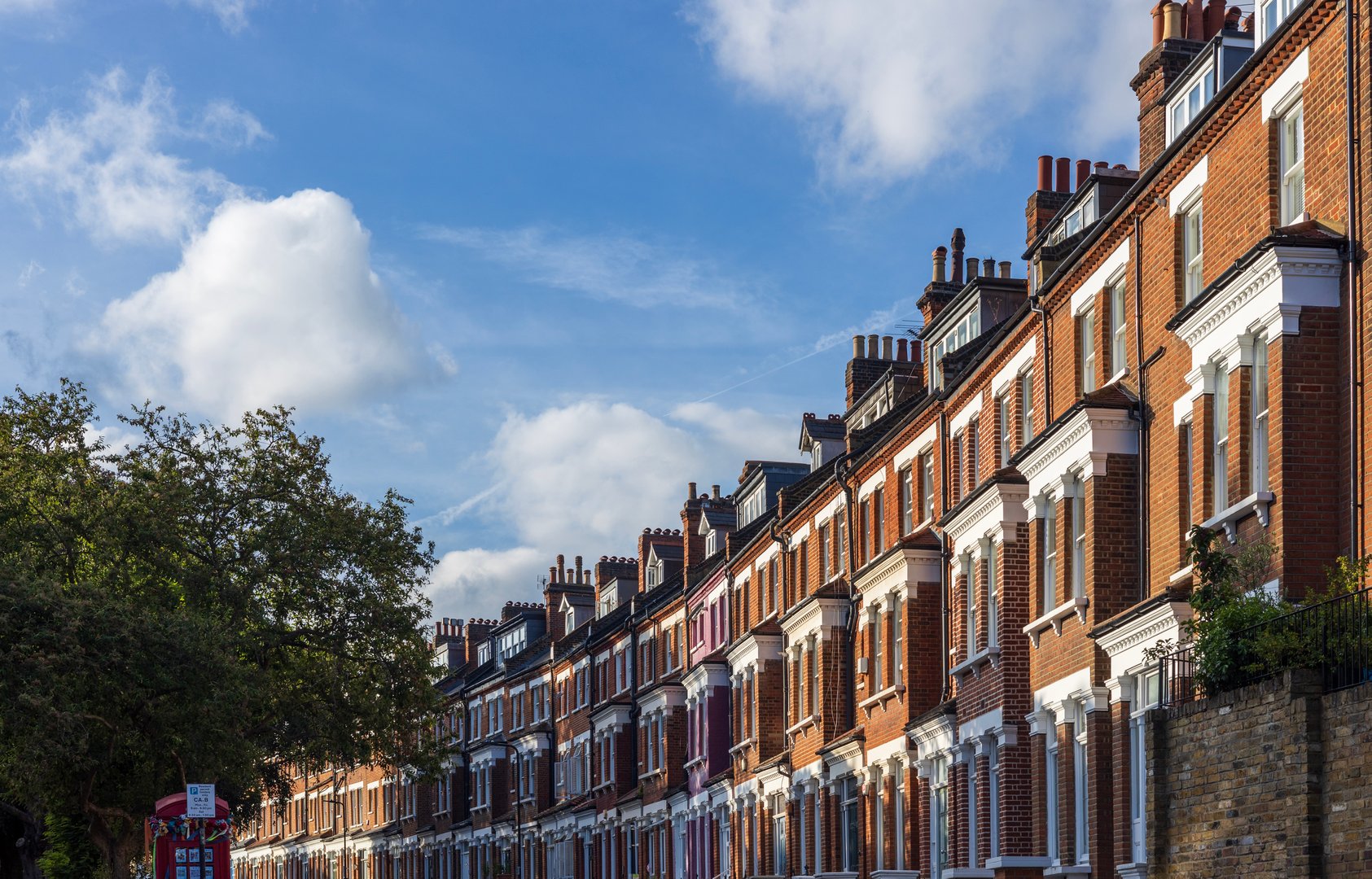 Central London real estate - a row of terraced houses against summer blue sky.