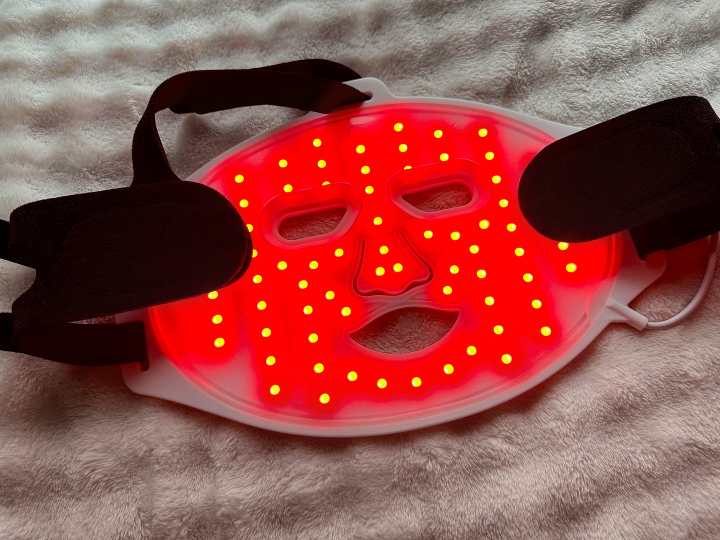 Led light therapy face mask on soft fabric, above view. Beauty treatment
