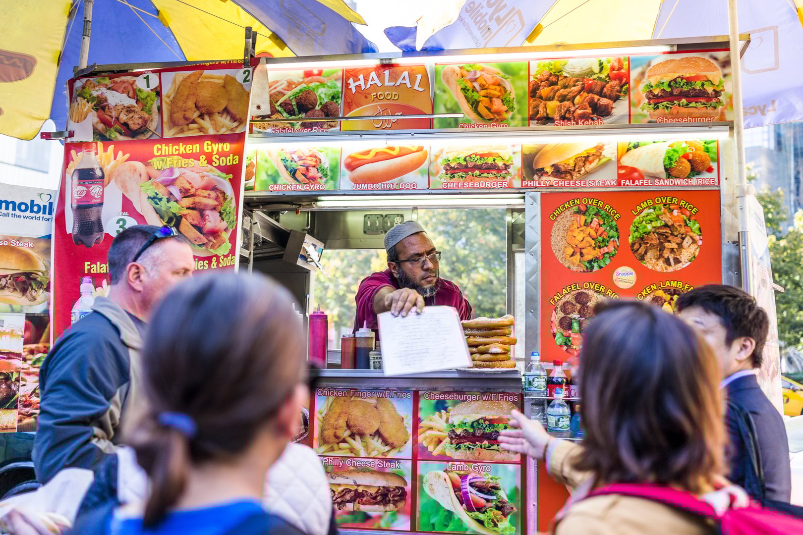 New York City: Columbus Circle in Midtown Manhattan NYC, closeup of Halal Food Truck stand with sign, seller person handing menu to customers