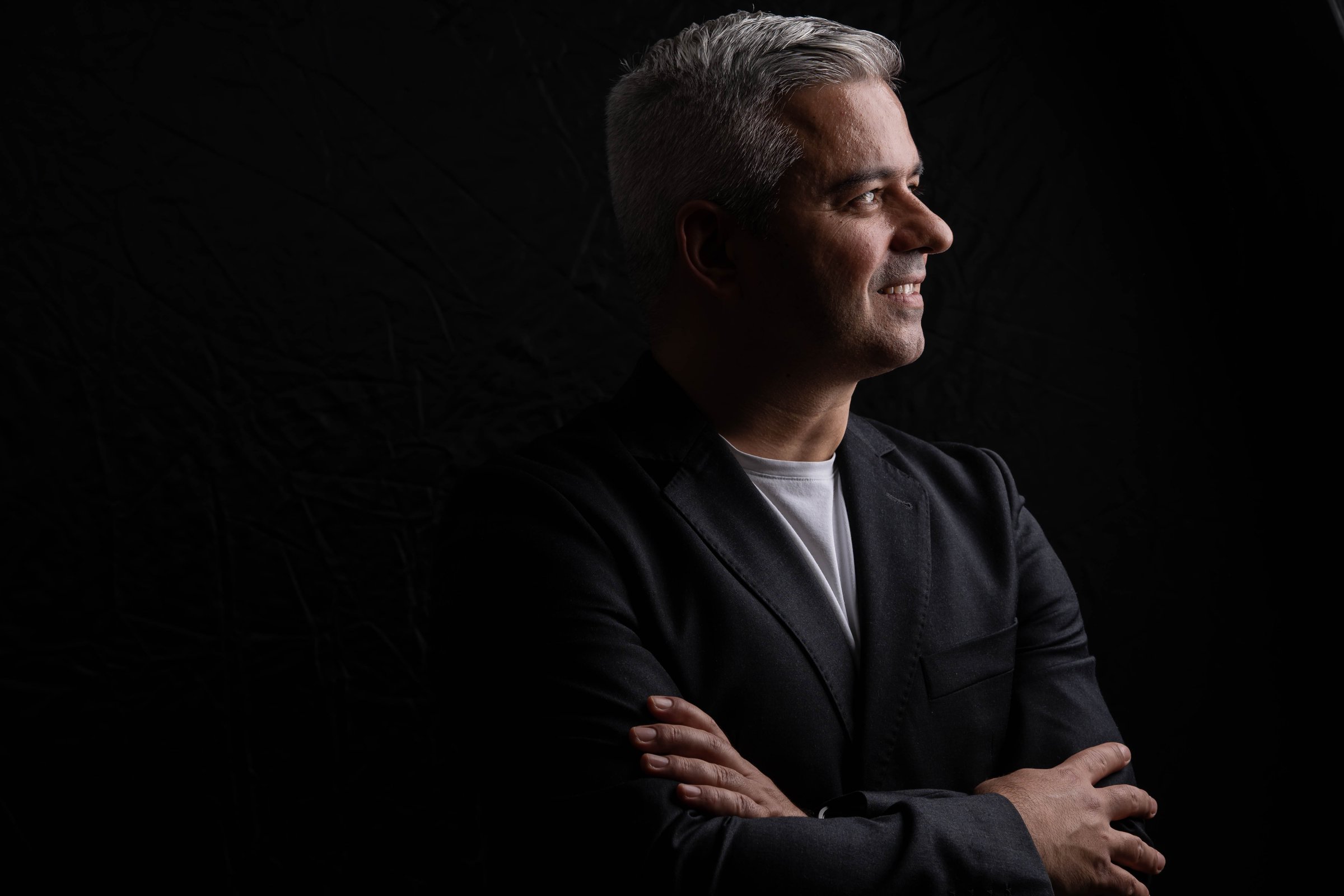 Middle-aged good looking man posing in front of a black background with copy space. Chiaroscuro