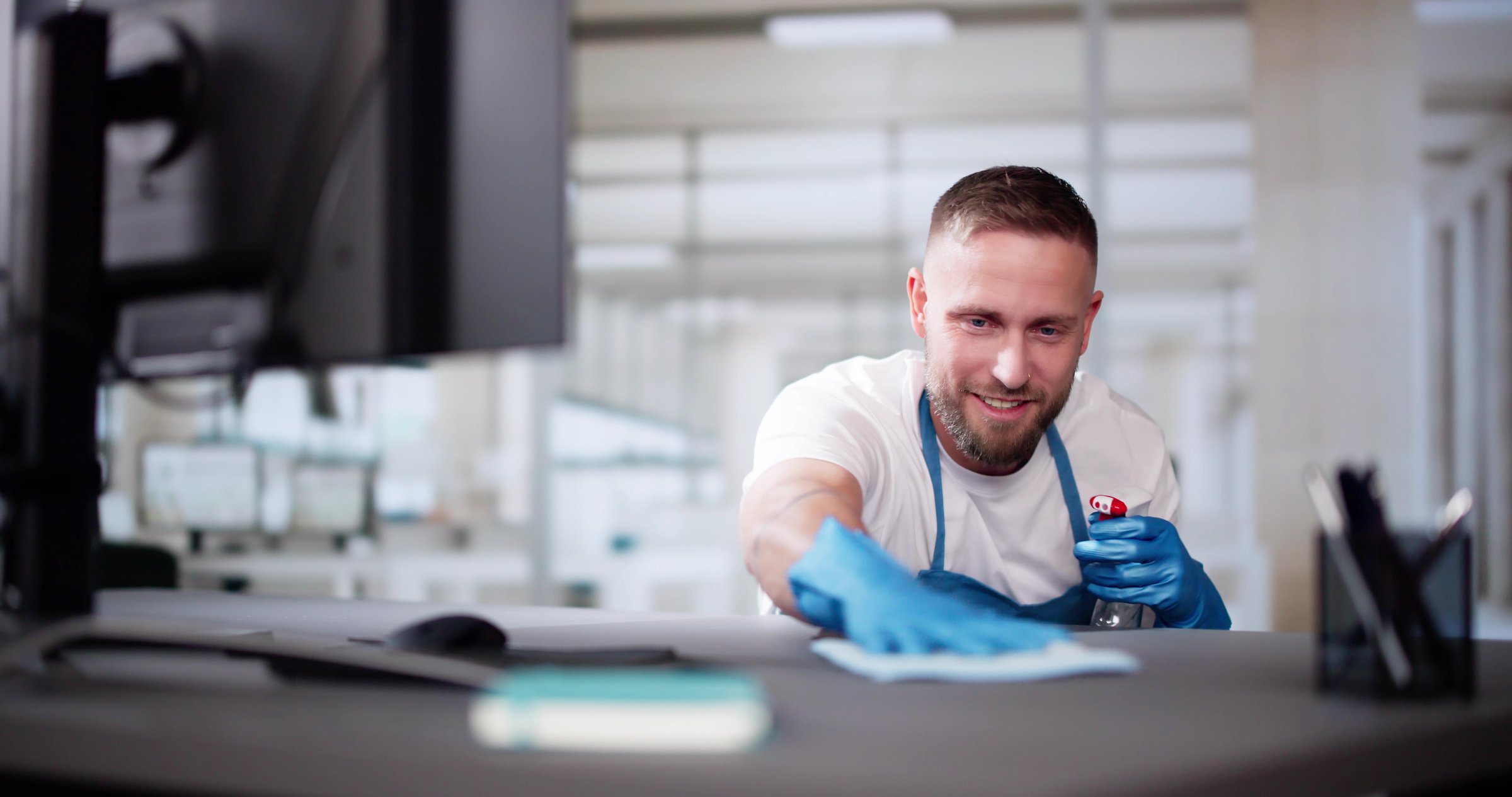 Janitor Cleaning White Desk In Modern Office