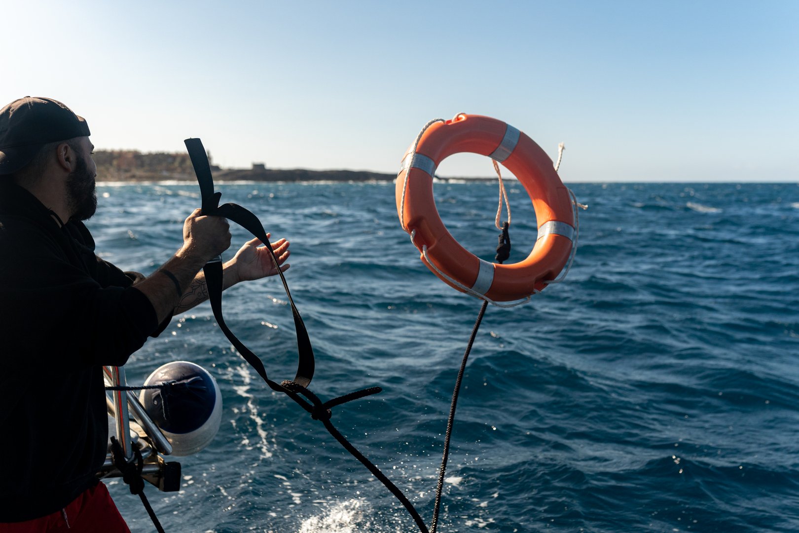 Sailor is throwing a lifebuoy into the ocean from a diving boat