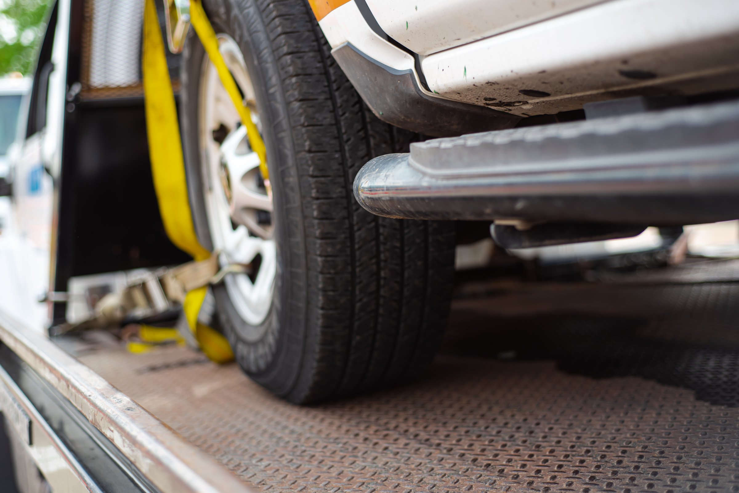 Yellow ratchet strap tie down pickup truck to flatbed rollback slide tilt tray of service tow truck from accident event to mechanic shop, collision help, roadside assistance, insurance claim. USA