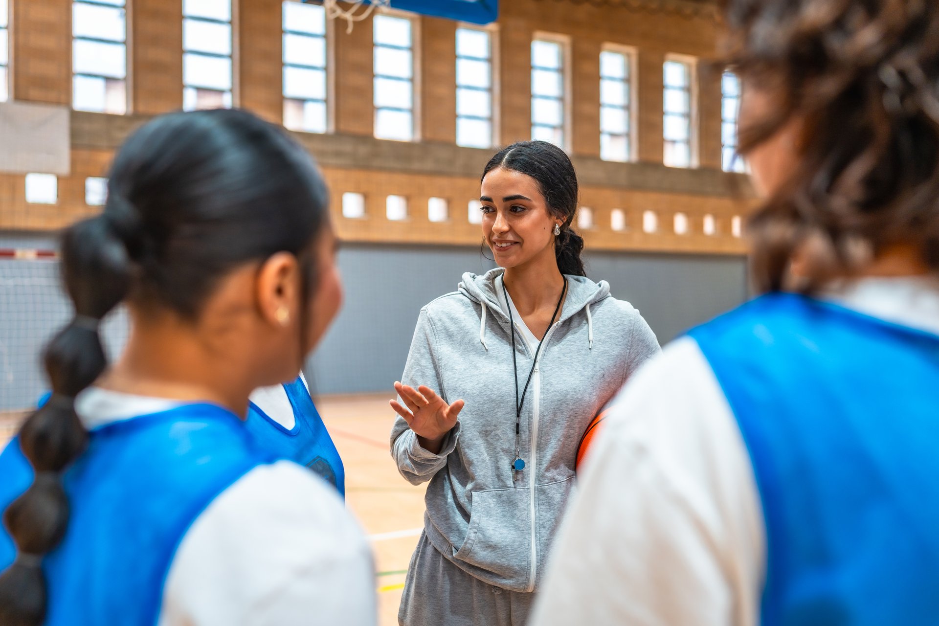 Female basketball coach explaining game strategy to her team during a time out in a basketball court