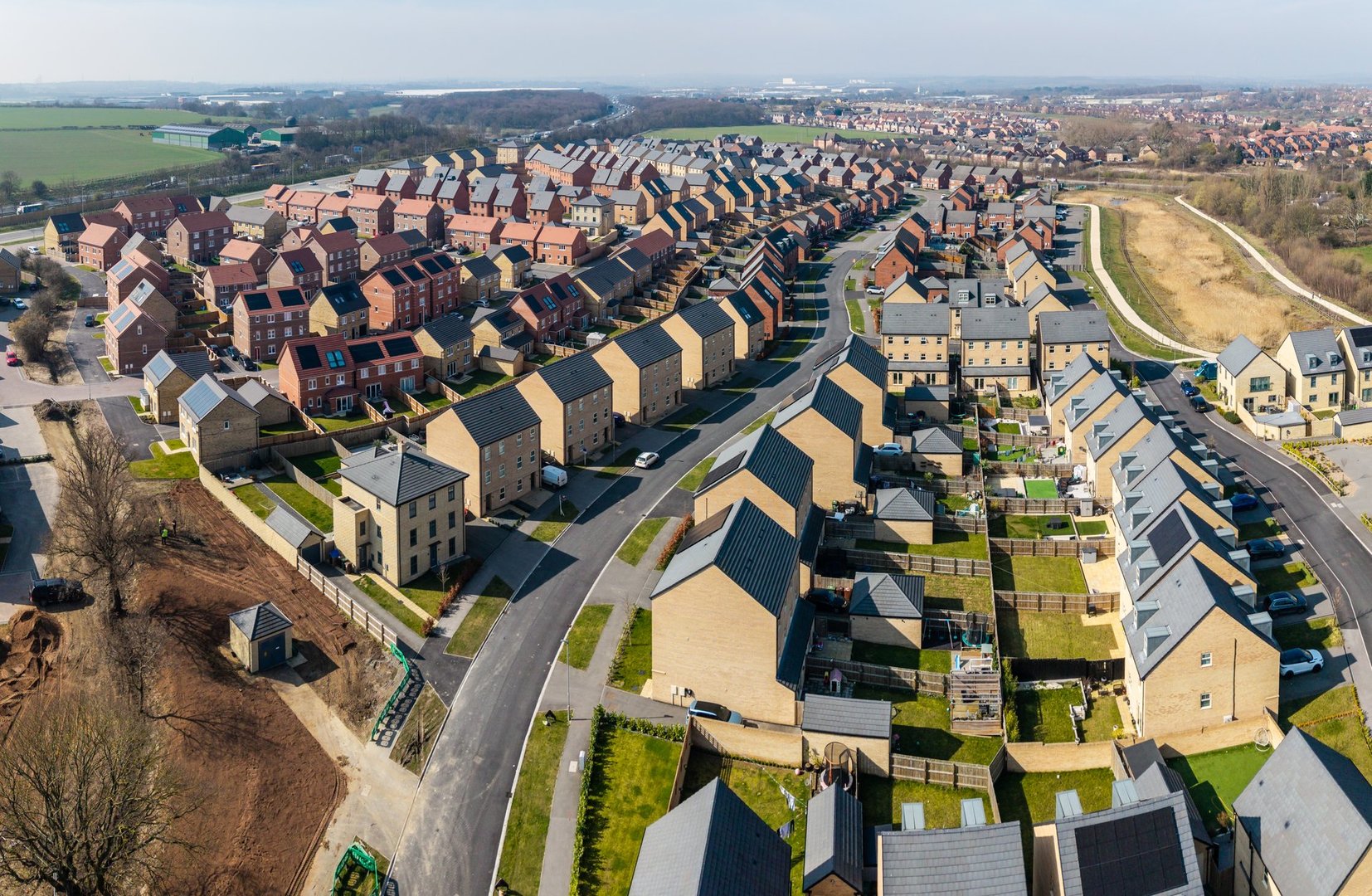 Aerial panorama landscape view of a large new build housing development on green belt land due to a housing shortage with characterless design for first time buyers