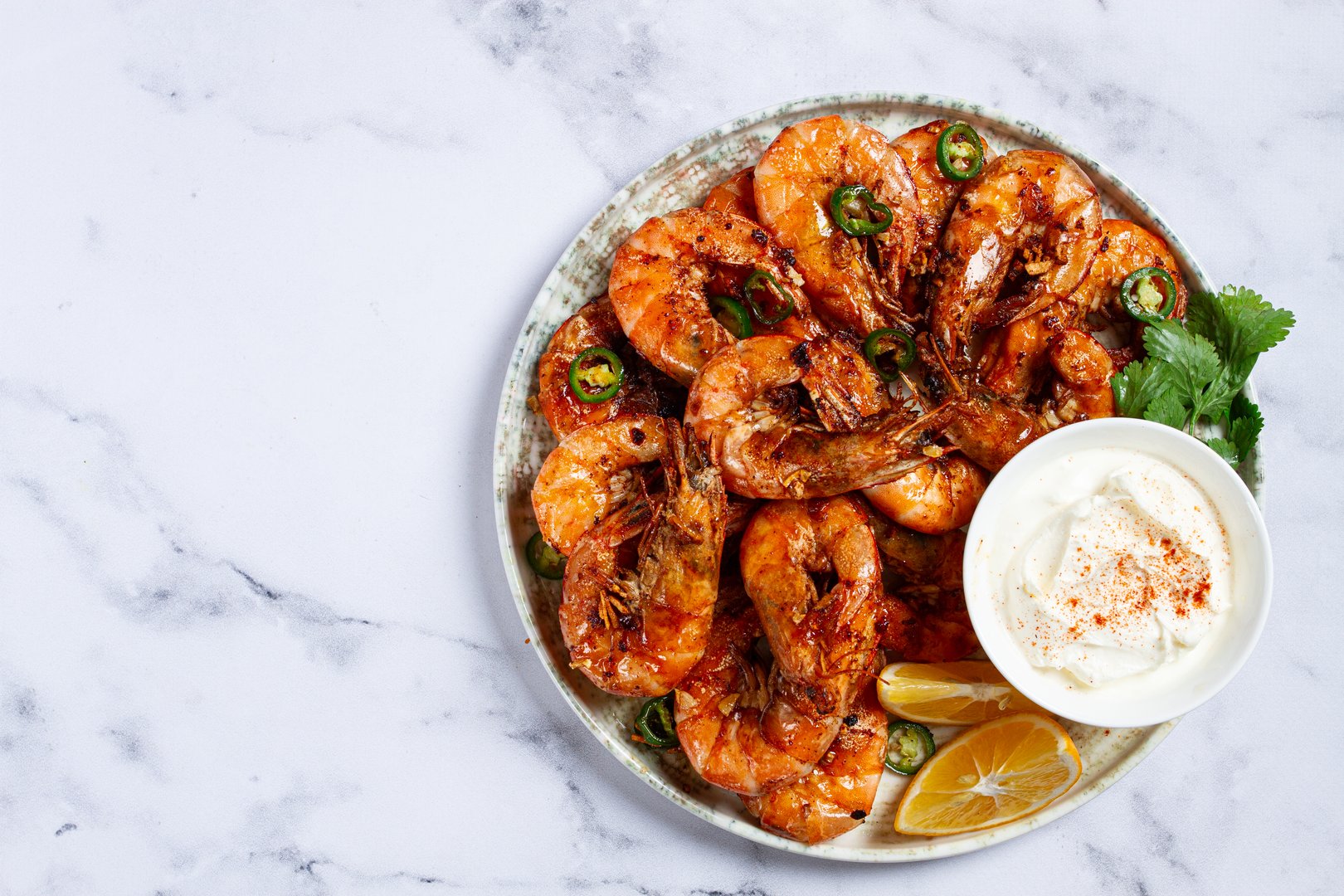 Grilled shrimps served with hot sauce and slices of fresh lemon