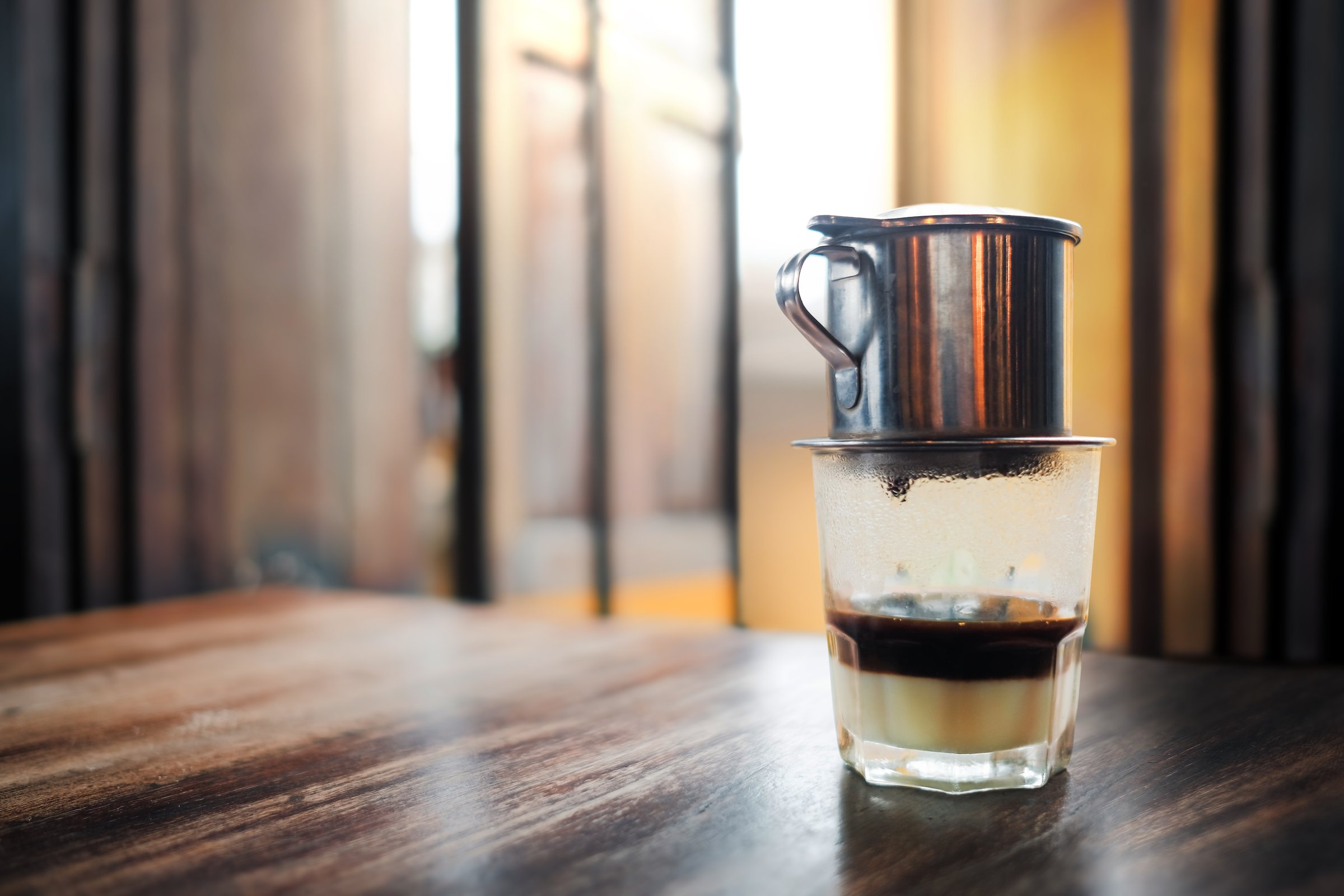 Vietnamese Coffee on Wooden Table. Traditional Hot Drinks in Vietnam. Black Coffee Dripping into the Cup