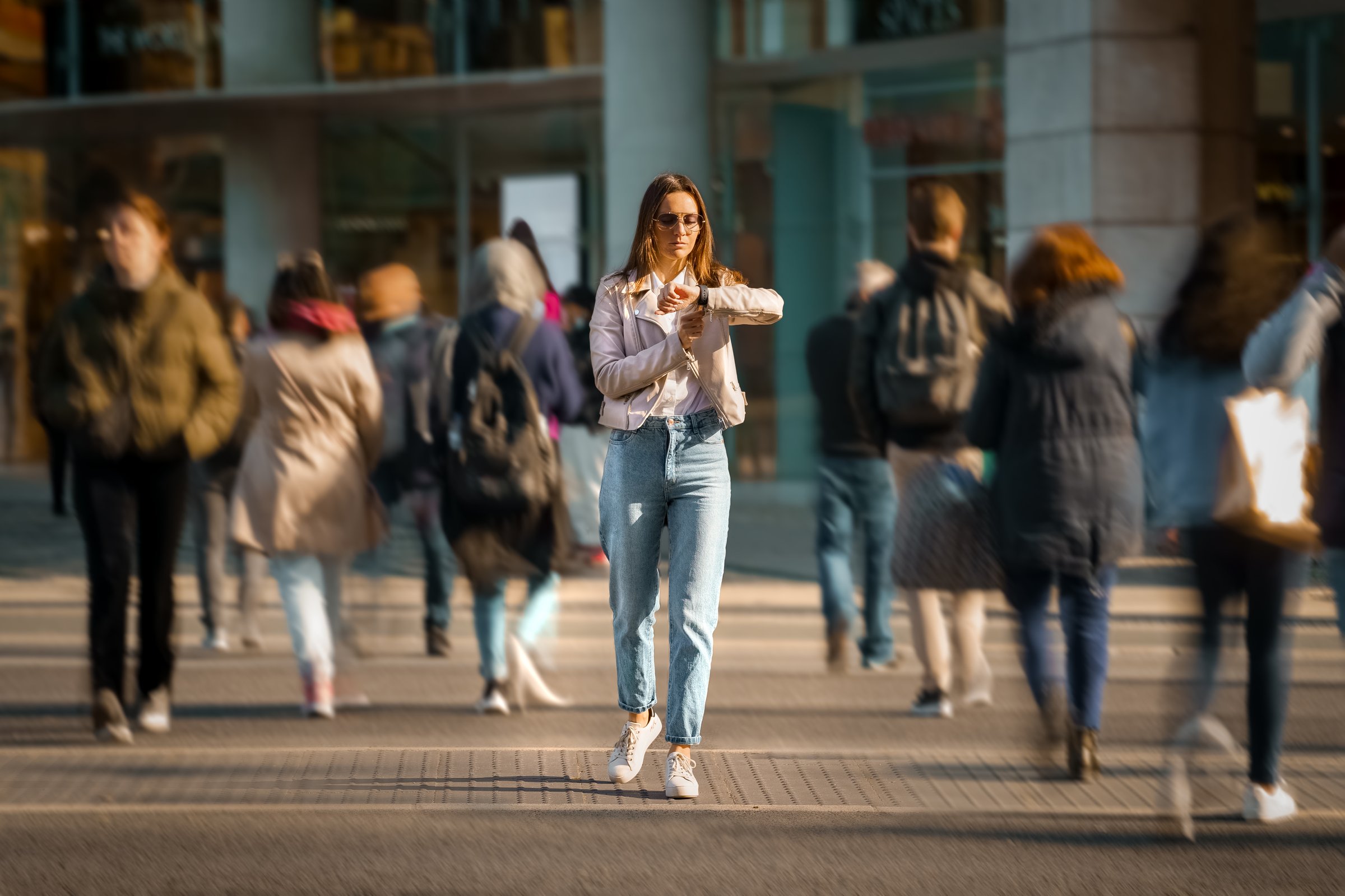 Young woman walking in the middle of crowded street and looking time at hand watches. Big city life. High quality photo