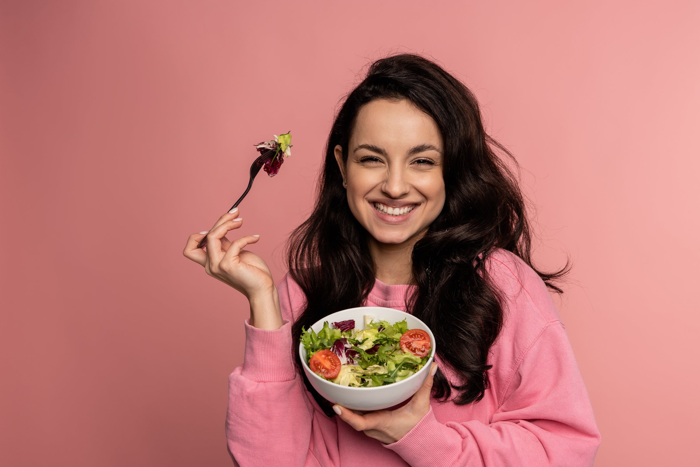 Portrait of a pleased lady eating vegetable salad