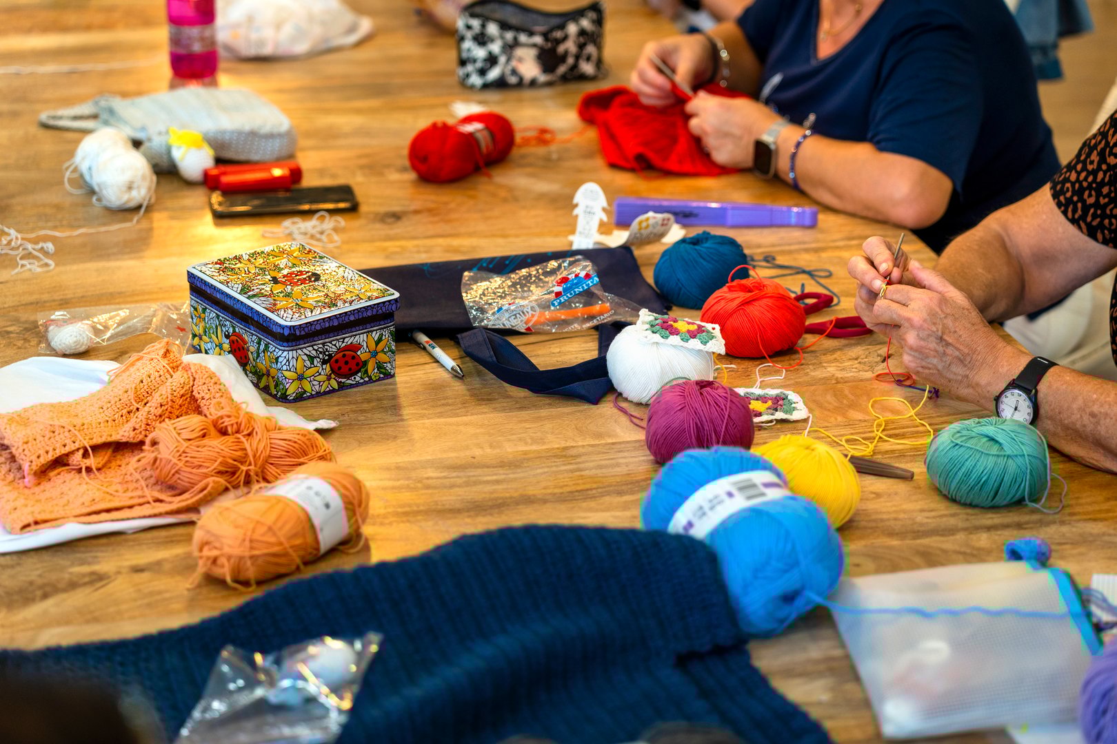 Crochet club. Ladies crocheting with colored wool.