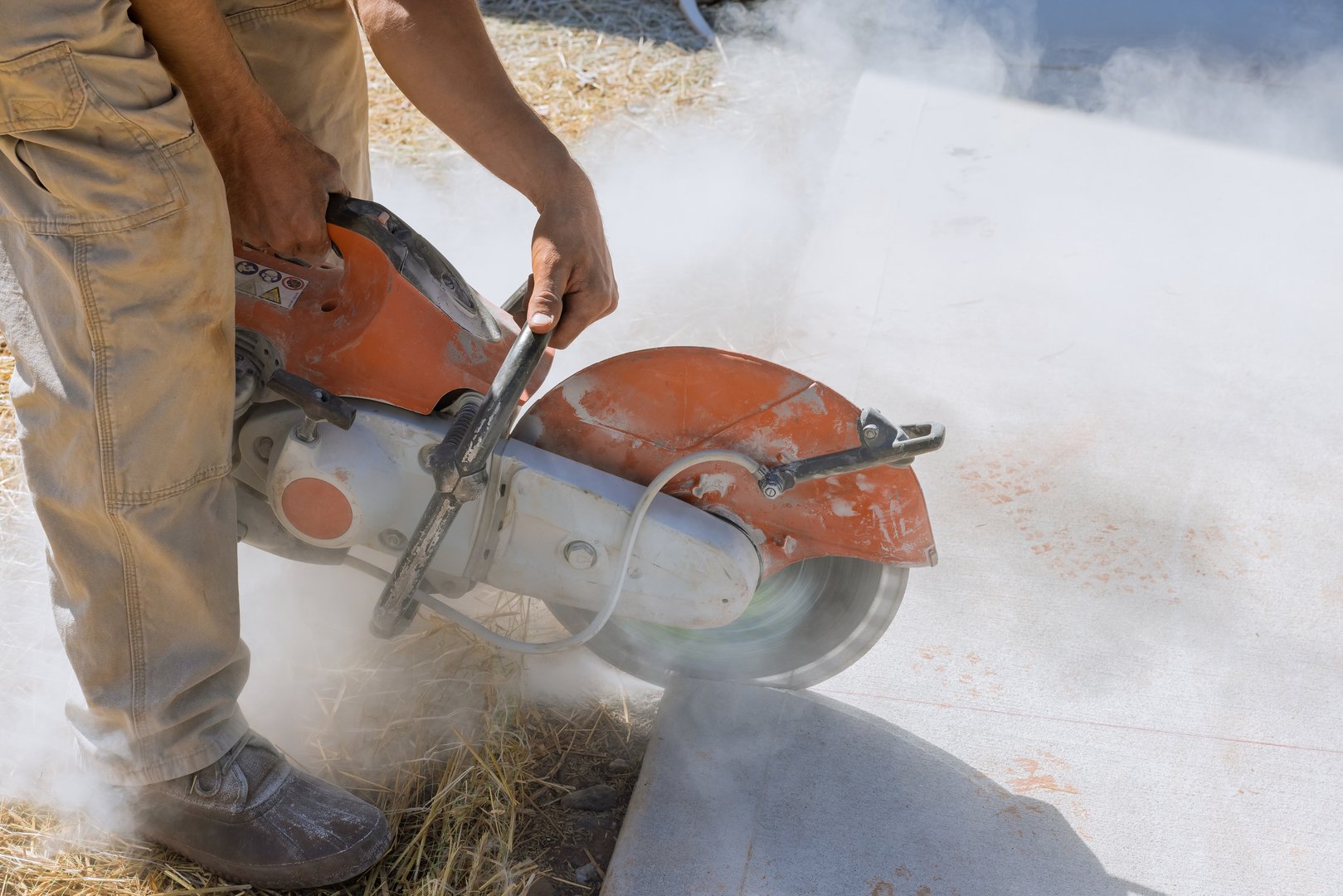 Construction worker cutting concrete paving stabs for sidewalk using cut off diamond bladed saw.