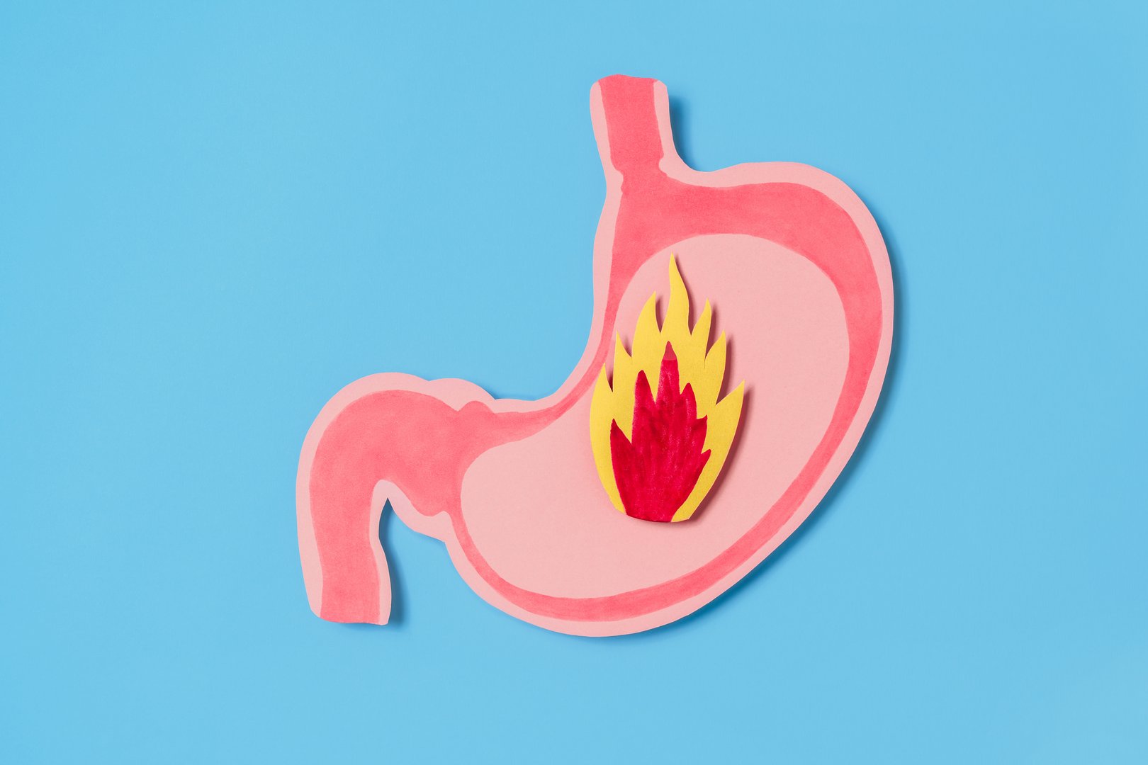 A pink stomach cutout with a flame symbolizing acid reflux or indigestion or hurtburn