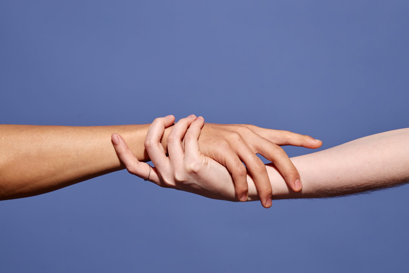 Close-up of two hands gently embracing, symbolizing unity and connection between diverse individuals. Capturing the simplicity and strength of human touch against plain background