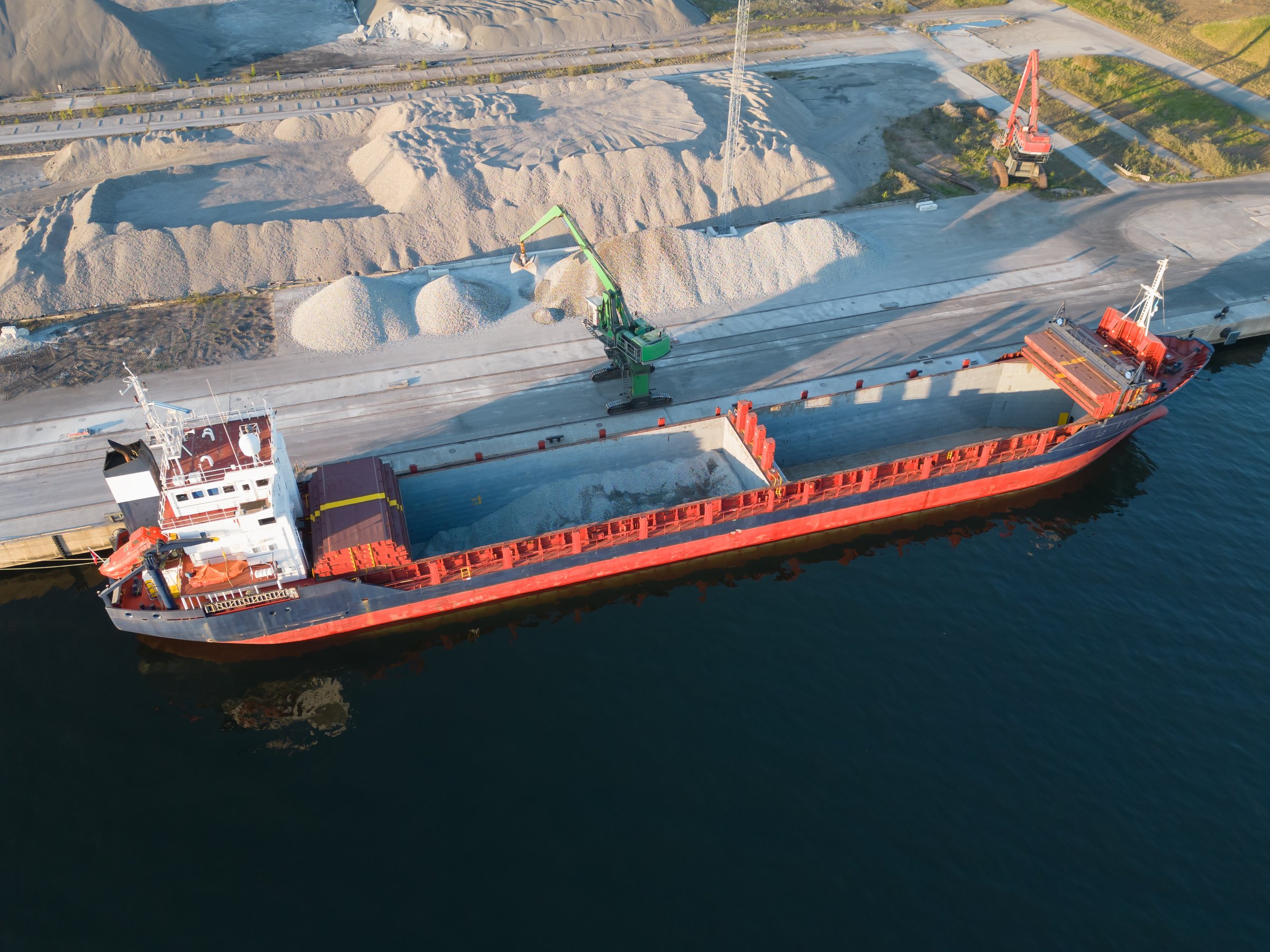 Drone view: a bulk carrier takes on tons of crushed stone at the port of Muuga. The large-scale loading demonstrates the Estonian port's activity.