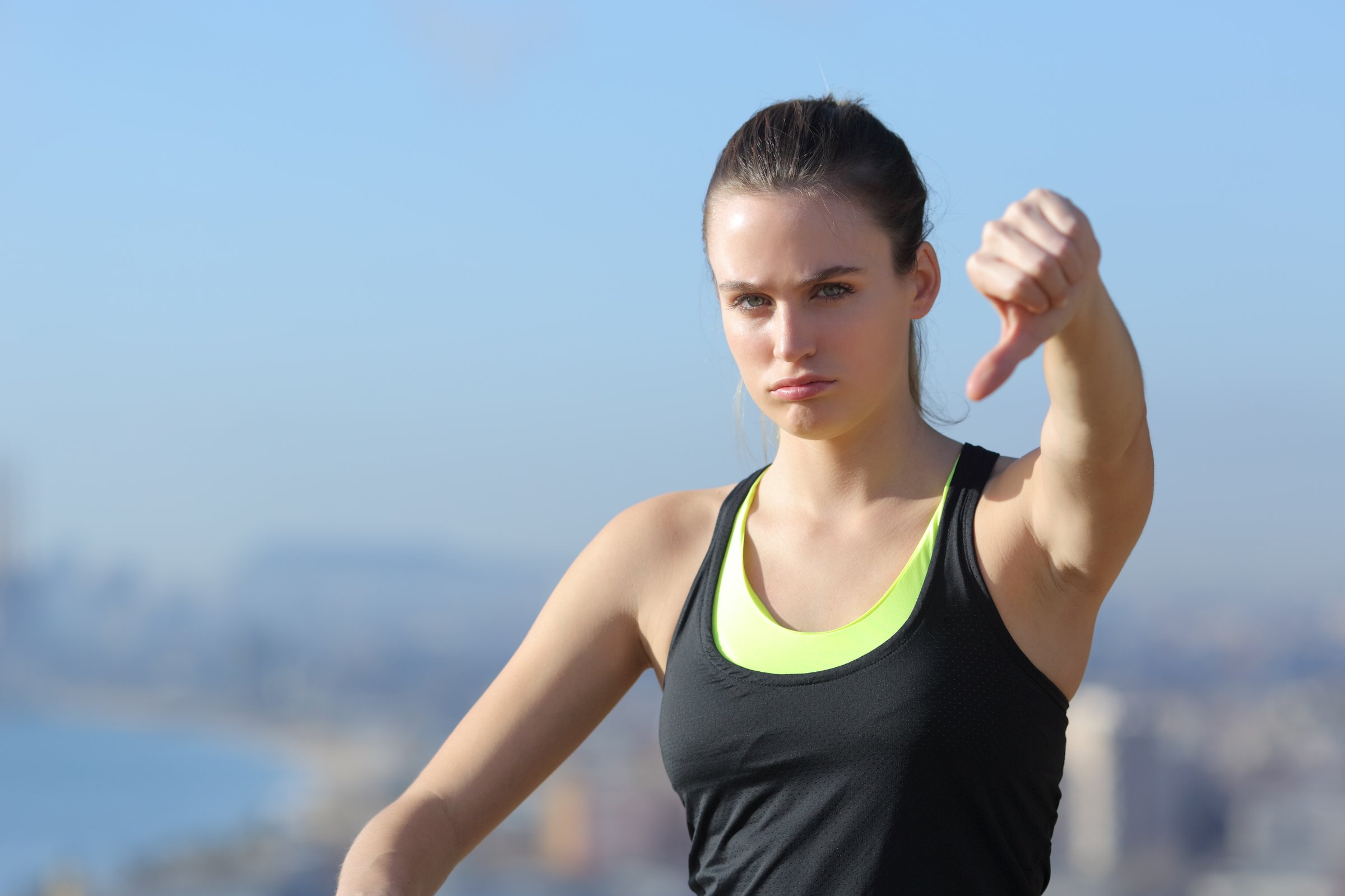 Angry sportswoman gesturing thumbs down in city outskirts