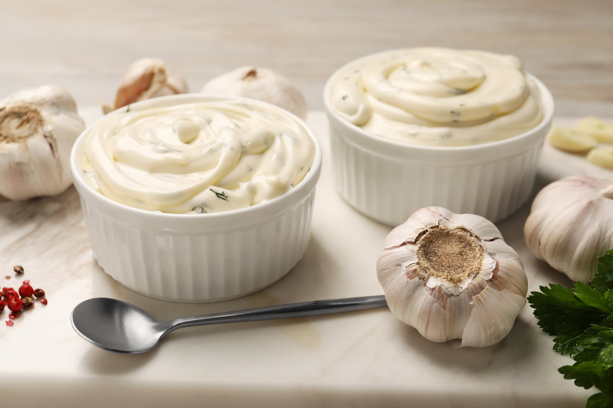 Tasty sauce with garlic and spoon on table, closeup