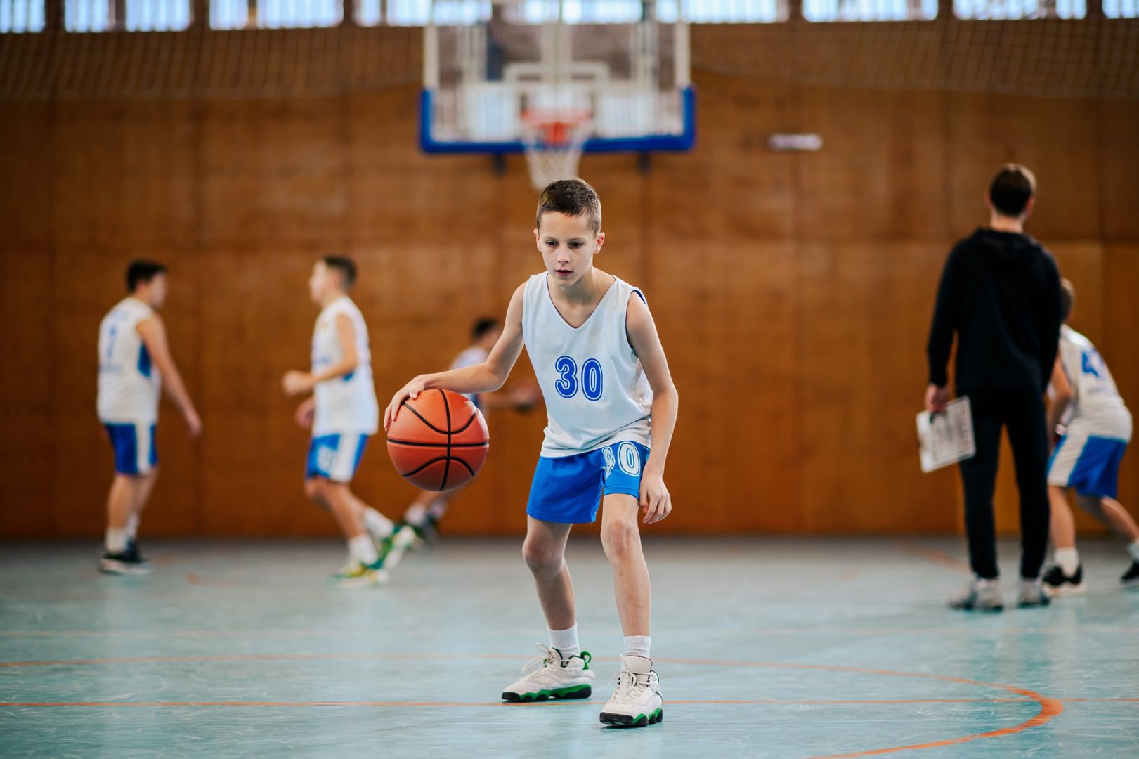 Energetic young player dribbles a basketball on the court, highlighting the dynamic nature of youth sports