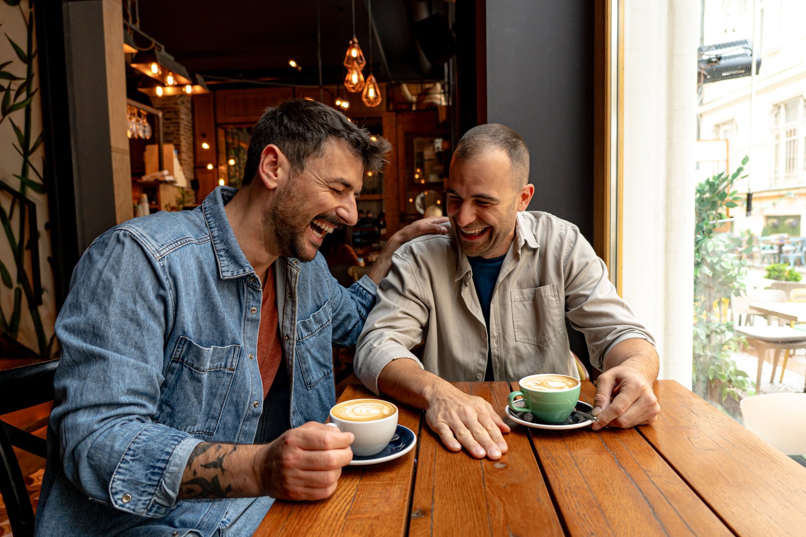 Two male friends enjoying a relaxing time together, sharing stories and laughter over coffee in a cozy cafe
