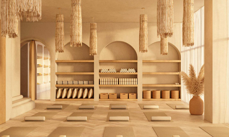 A serene yoga studio with mats, cushions, and woven decor elements. Shelves hold towels and baskets, creating a calming ambiance.