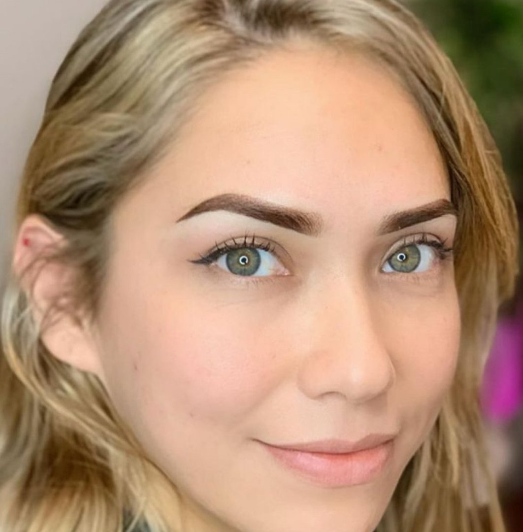 Young woman during procedure of permanent eyebrow makeup in beauty salon, closeup