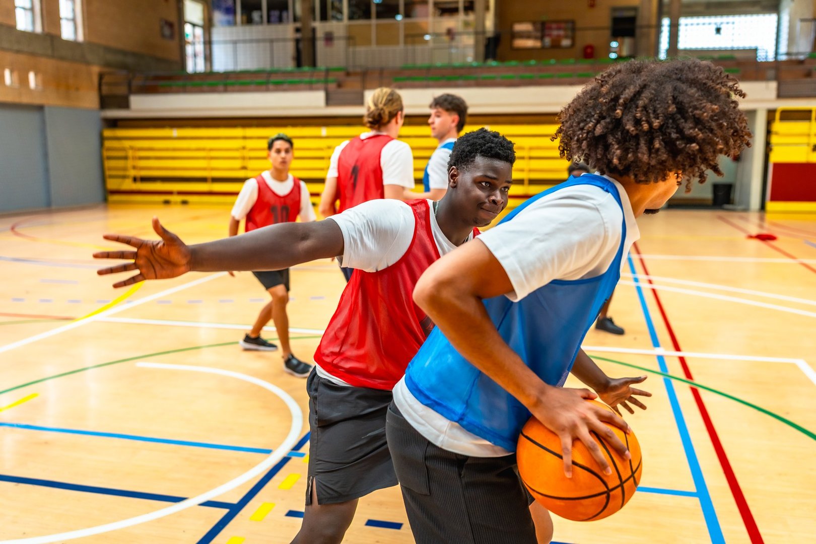 Teenagers engaging in an intense basketball game on a wooden court, skillfully dribbling, passing, and showcasing teamwork