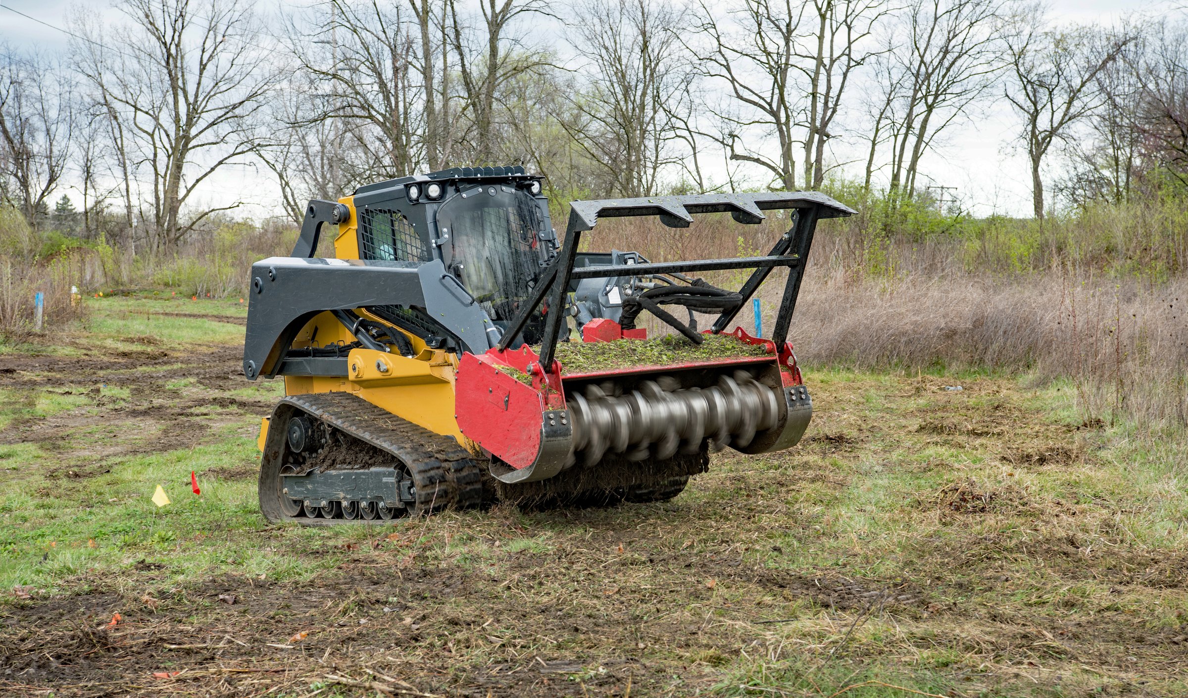 Forestry mulcher actively mulching weeds from field in preparation for new housing development.