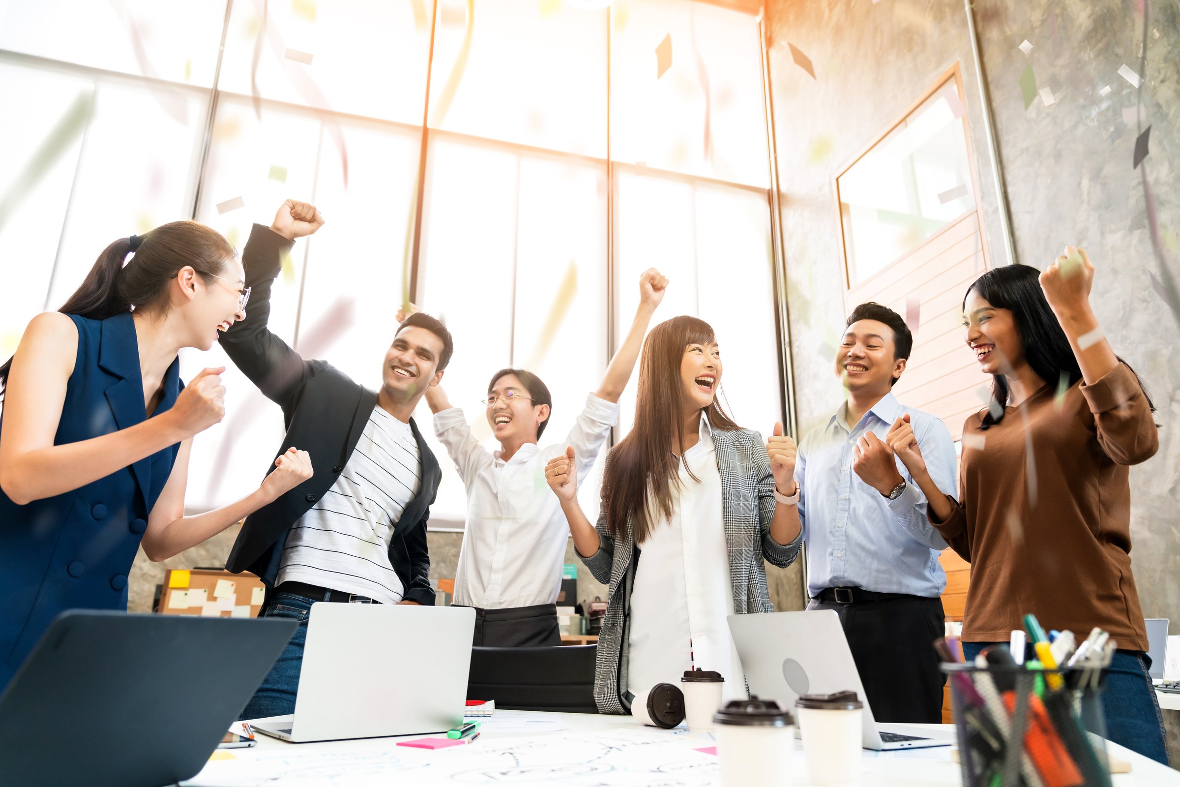 Multi-ethnic businesspeople cheering with business project successful
