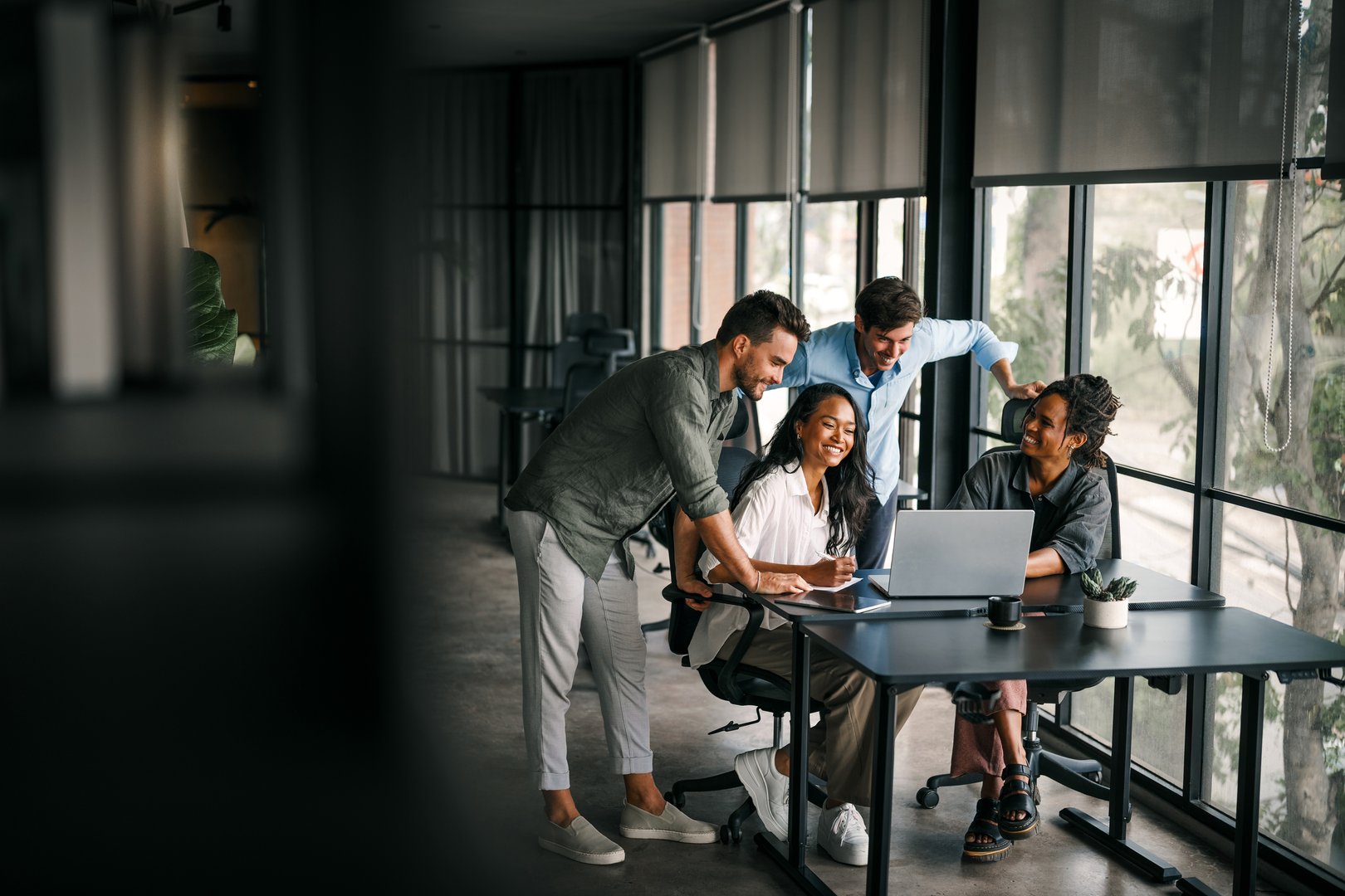 Mixed team of software engineers brainstorming ideas for new code library in front of computer screens compiling algorithms. Diverse app developers collaborating on group project in it agency office.