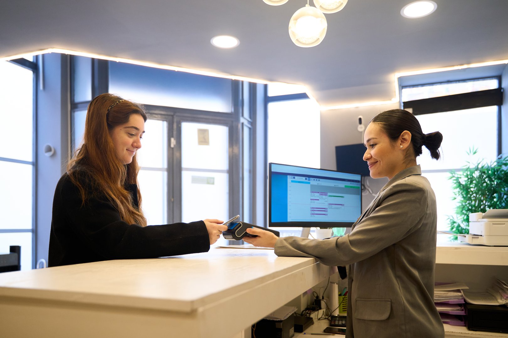 Patient making a contactless payment using smartphone at the dentist's office reception desk