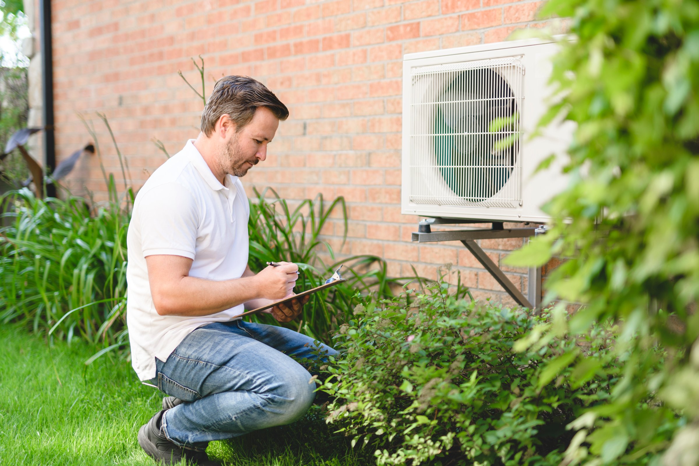 A technician working on air conditioning or heat pump outdoor unit