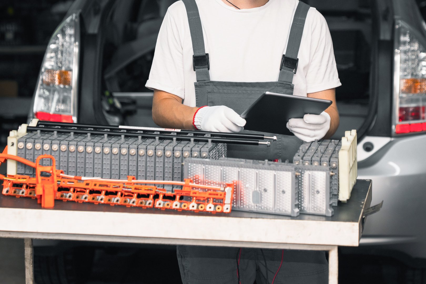 Serviceman repairs electric battery pack of hybrid car using digital tablet
