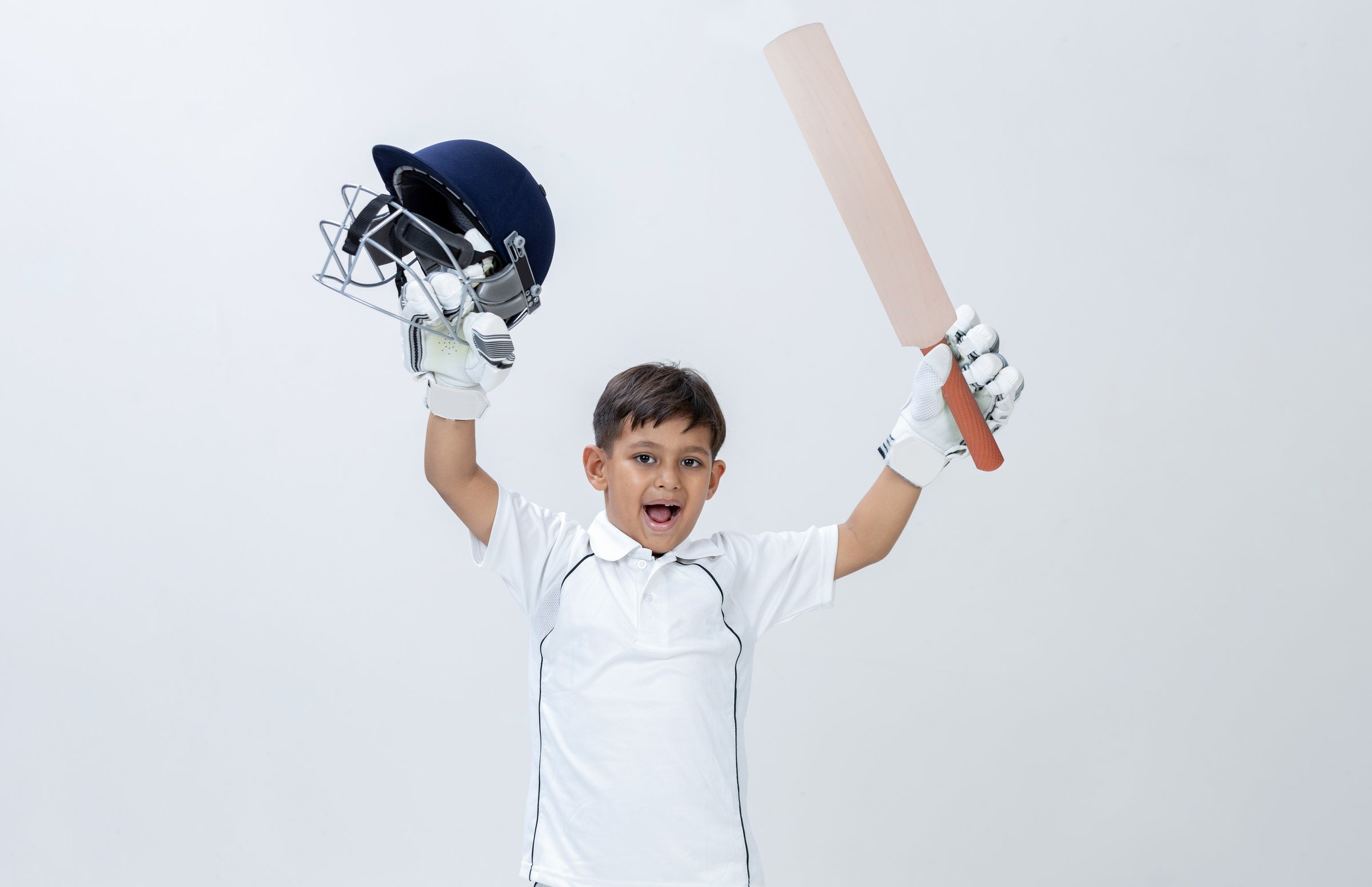 Kid in cricket dress holding bat and Helmet celebrating Century on isolated background Studio shot, cricket concept