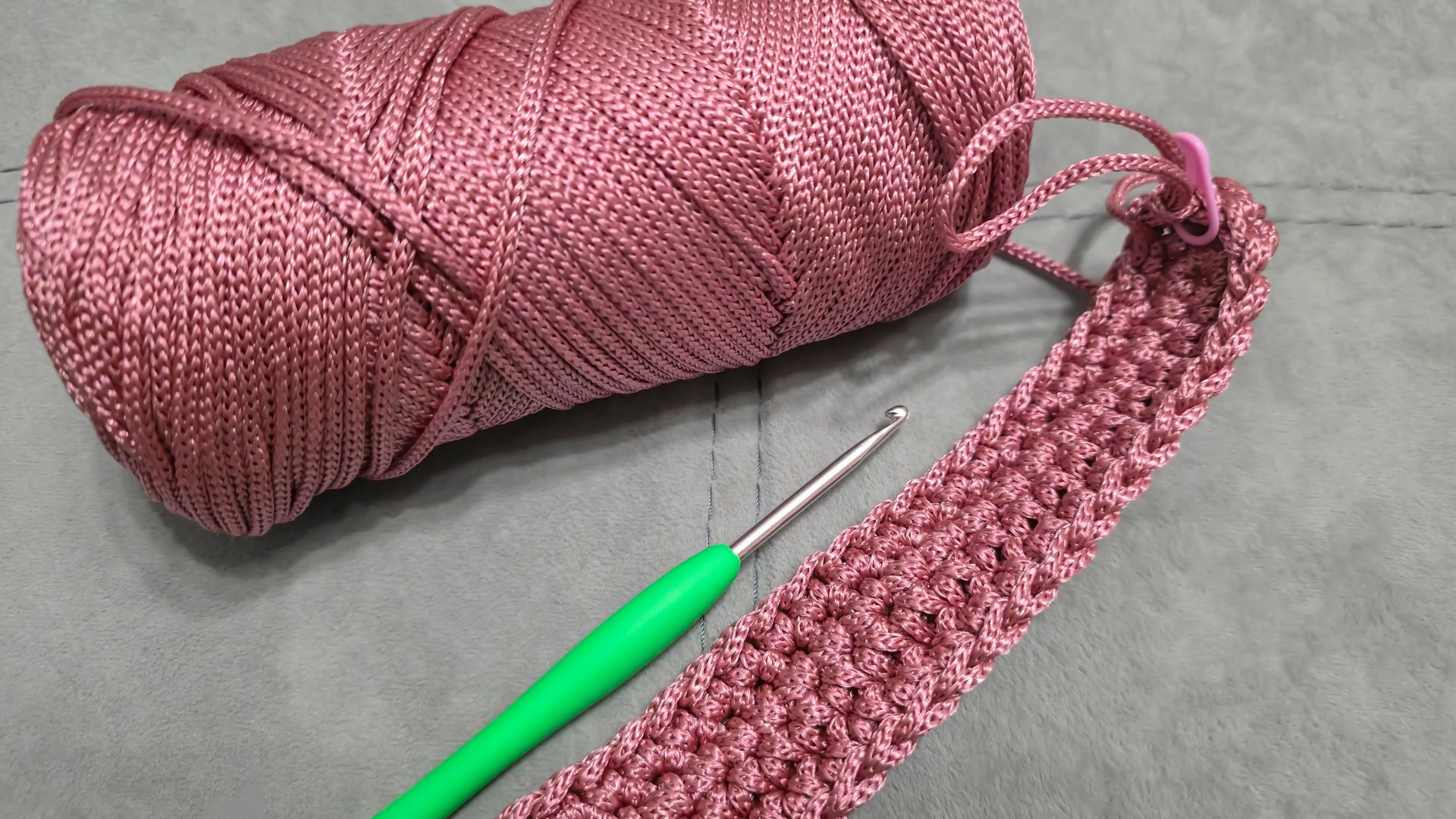 Knitting elements of a pink women's bag, hand knitting with a long handle. Step-by-step instructions. On a gray background.