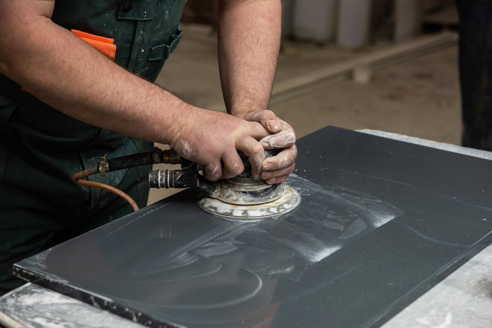 Stone furniture production. Worker polishes the surface of the facade with a grinder