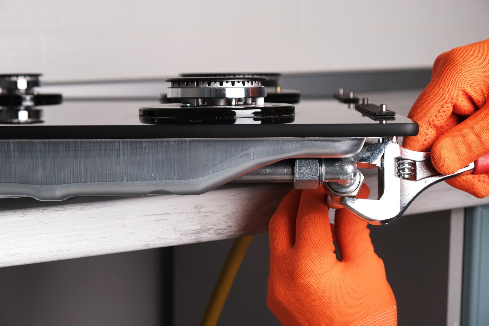 Connecting  gas hose to  hob, hands with an adjustable wrench close-up