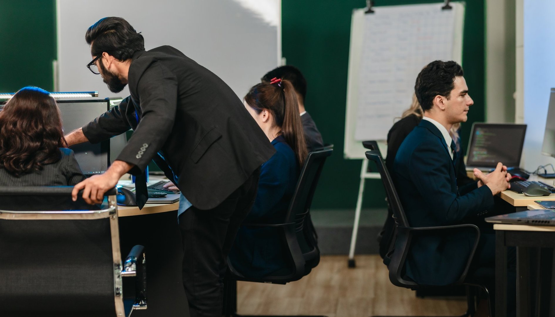 Professionals collaborate in  tech environment. Senior members coaching, mentoring, guiding colleagues through data analytics and software development. Knowledge sharing, leadership, technical growth