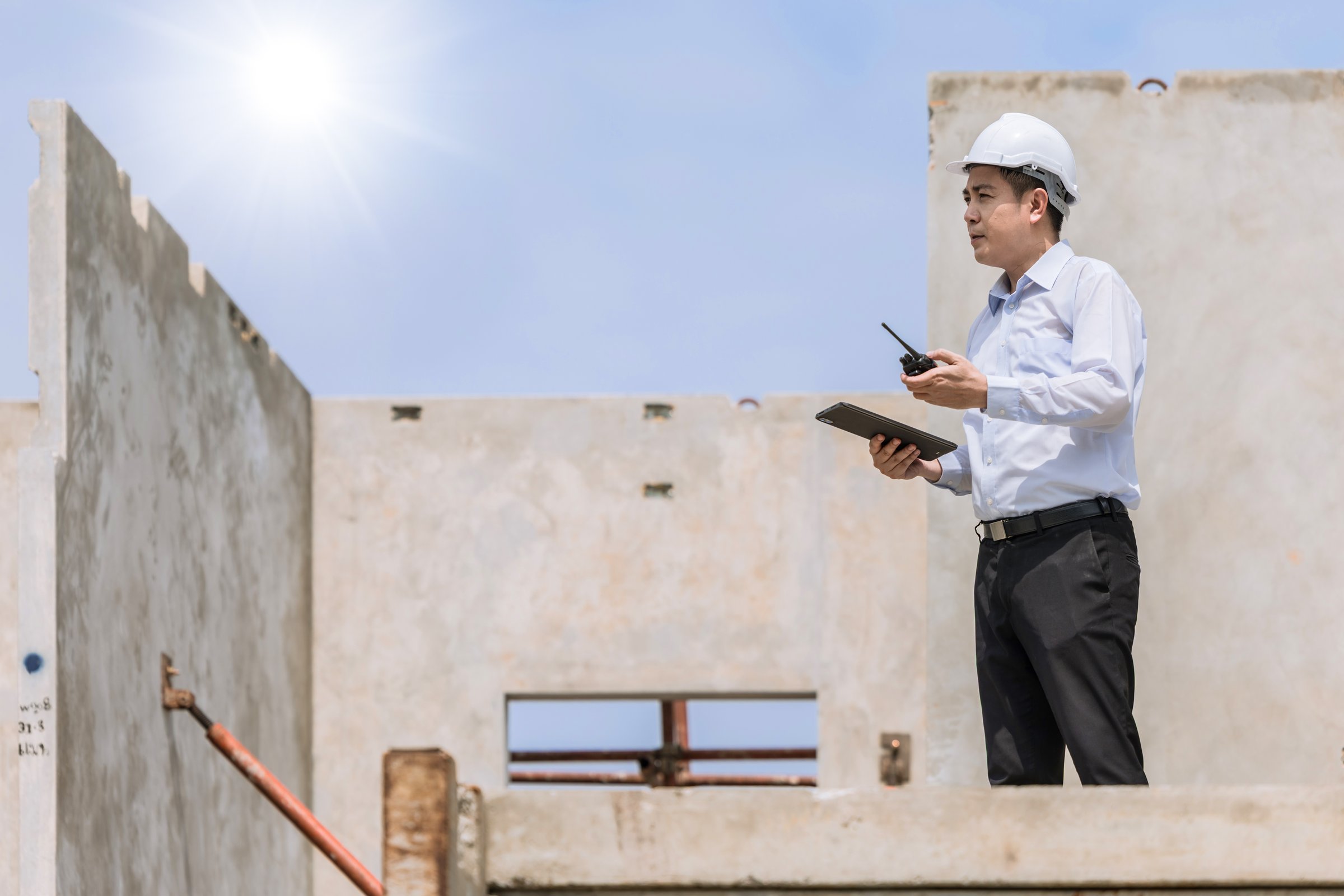 Asian engineer overseeing construction project at urban site professional environment high angle viewpoint