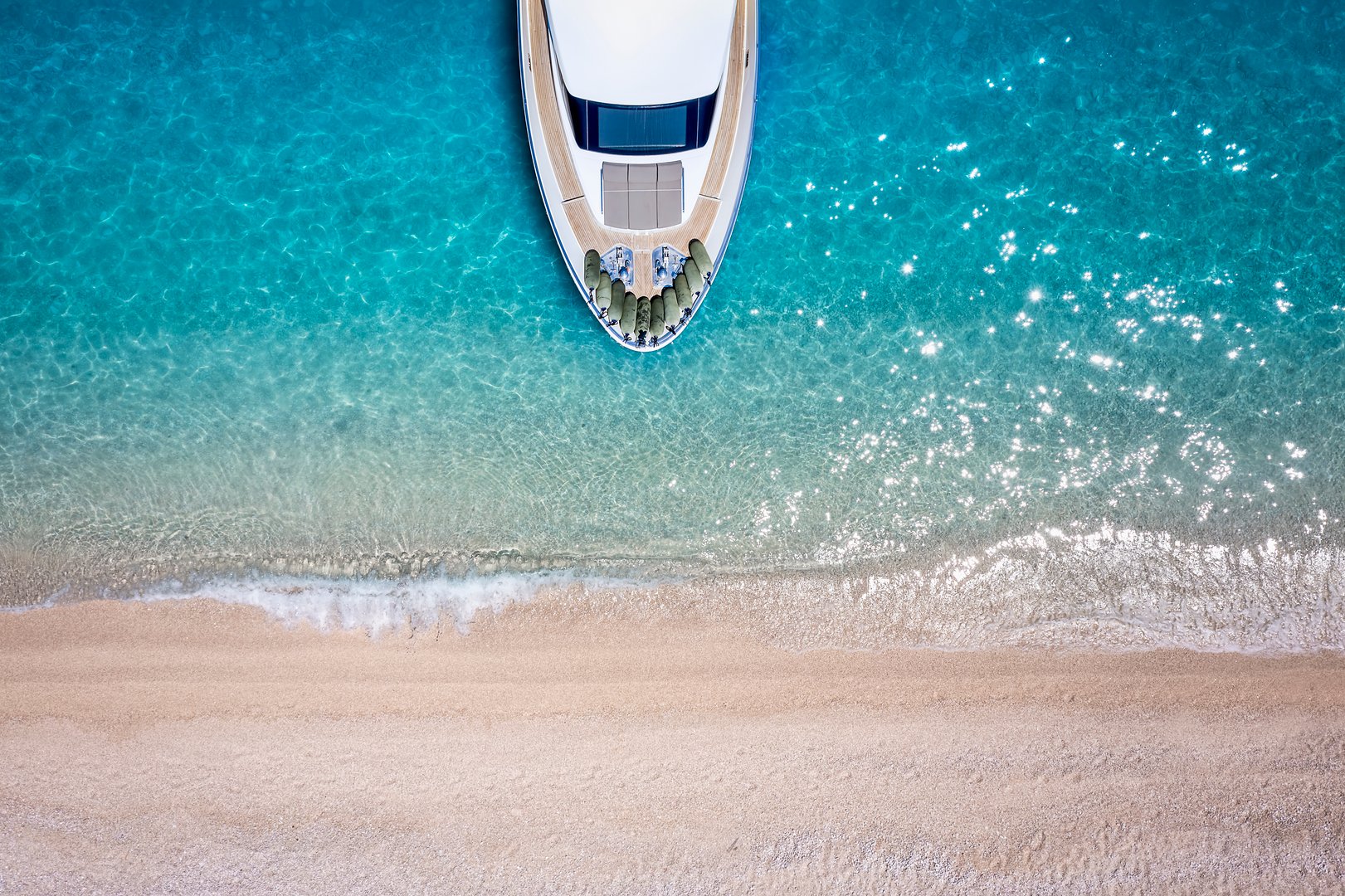 Aerial top down view of a luxury yacht moored at a paradise beach