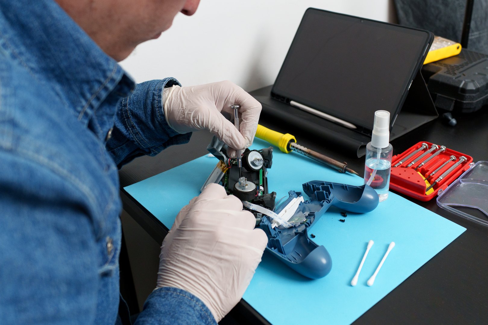 Close-up of electronic technician repairing a broken joystick using various tools