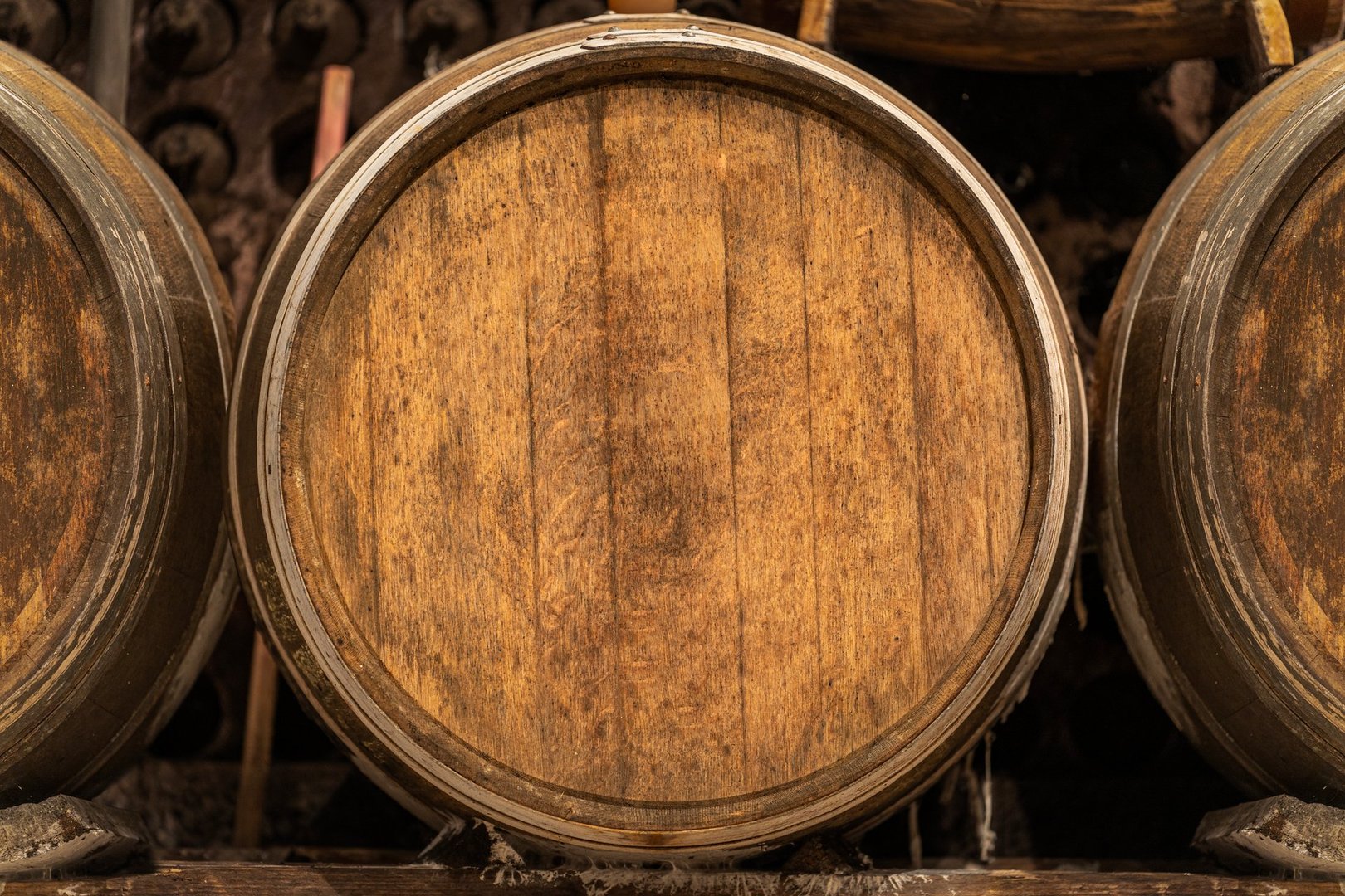 Oak barrels stacked inside a winery cellar, aging wine, representing the winemaking process