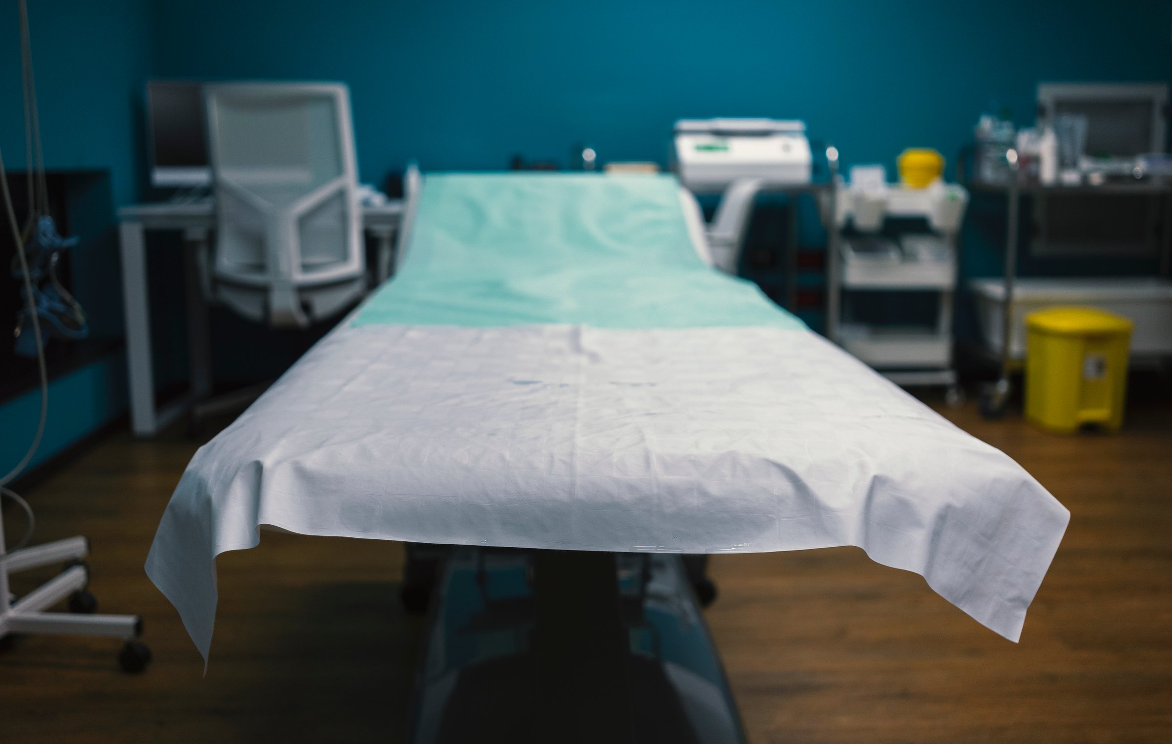 Details of the table in the clinic, focus on the front of the bed, clinical equipment in the background.
