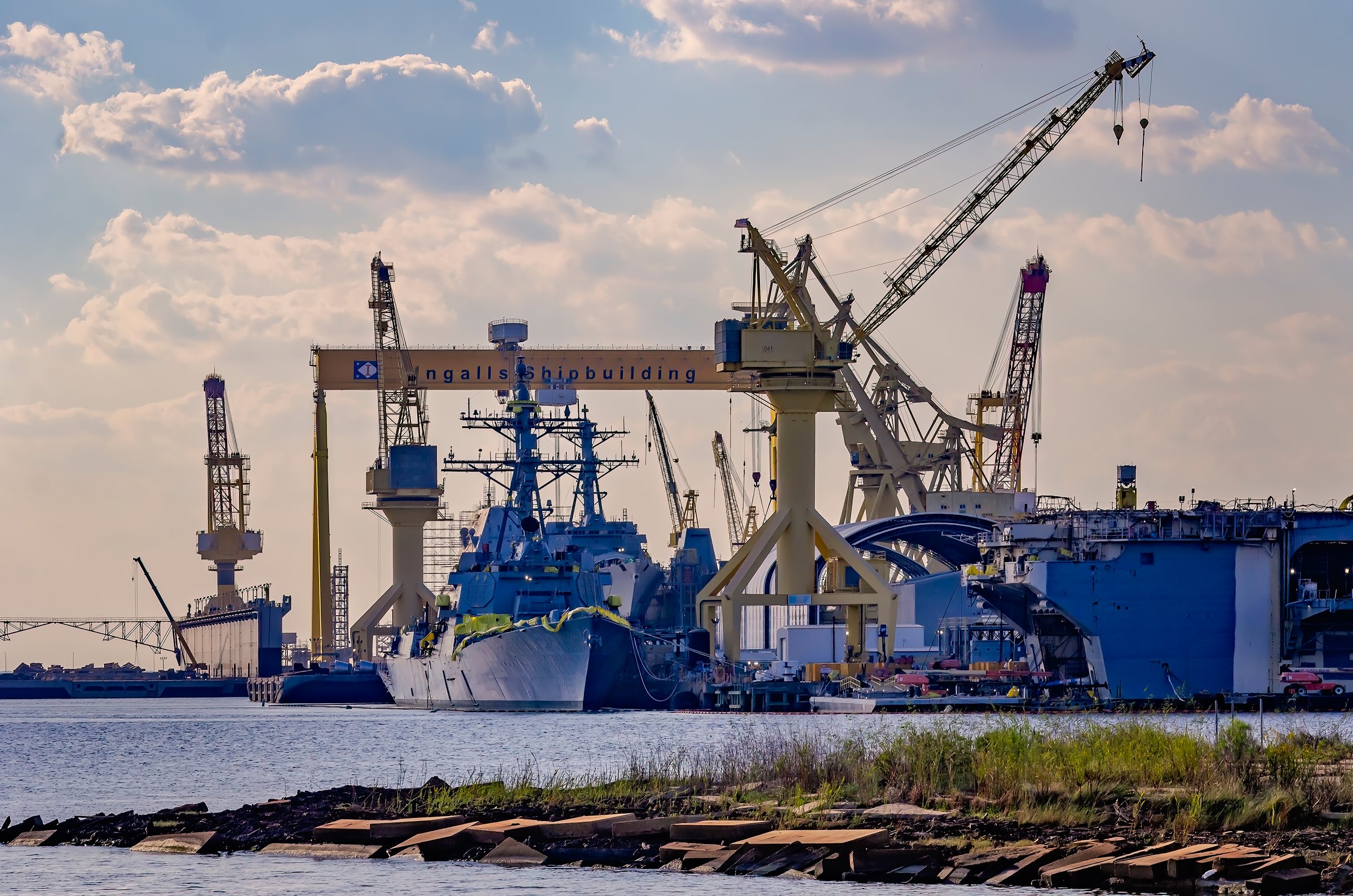 Pascagoula, Mississippi, USA - Oct. 9, 2024: Military warships are under construction at Ingalls Shipbuilding, a division of Huntington Ingalls Industries in Pascagoula, Mississippi. In the foreground is the Arleigh Burke-class guided missile destroyer Ted Stevens (DDG 128). Ingalls Shipbuilding was founded in 1938. The shipyard played a critical role in World War II, building more than 60 ships during the war. Today, Ingalls Shipbuilding continues to build warships for the United States Navy, United States Coast Guard, and the United States Marine Corps.