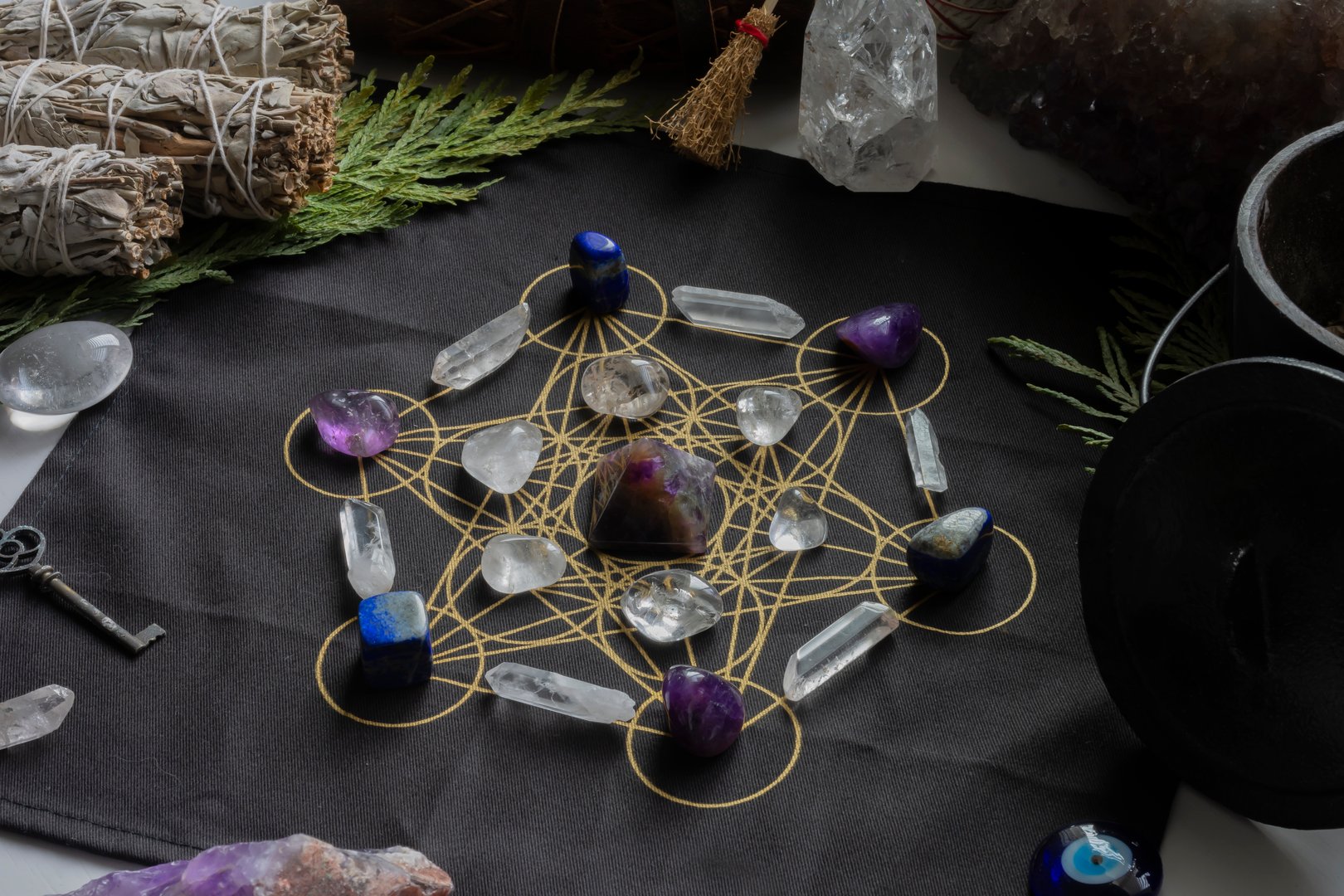 A top view image of a crystal healing grid with amethyst pyramid and sage.