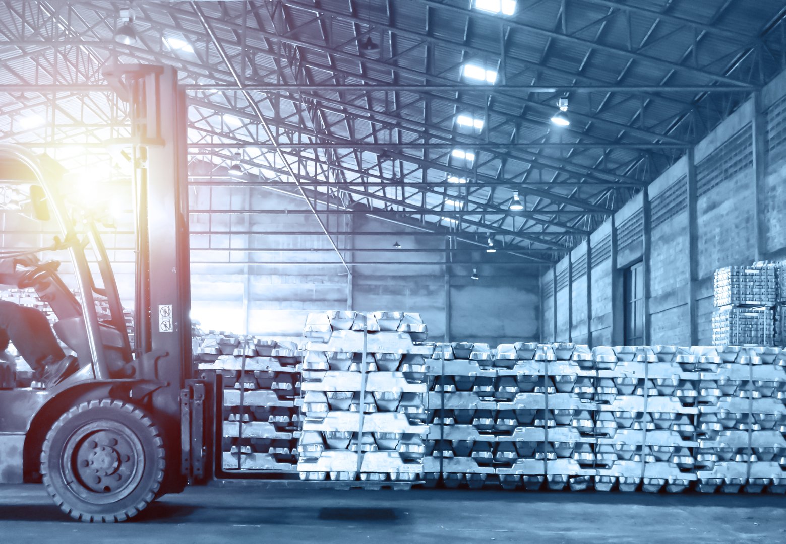 Forklift handling pack of aluminum ingot in warehouse. Distribution warehouse and industrial raw material logistics. Distribution warehouse and industrial raw material logistics.