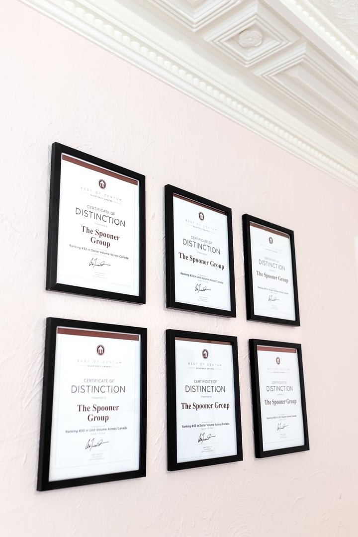 Six framed Certificates of Distinction from Barry Plant Agency Group hang on a textured wall.