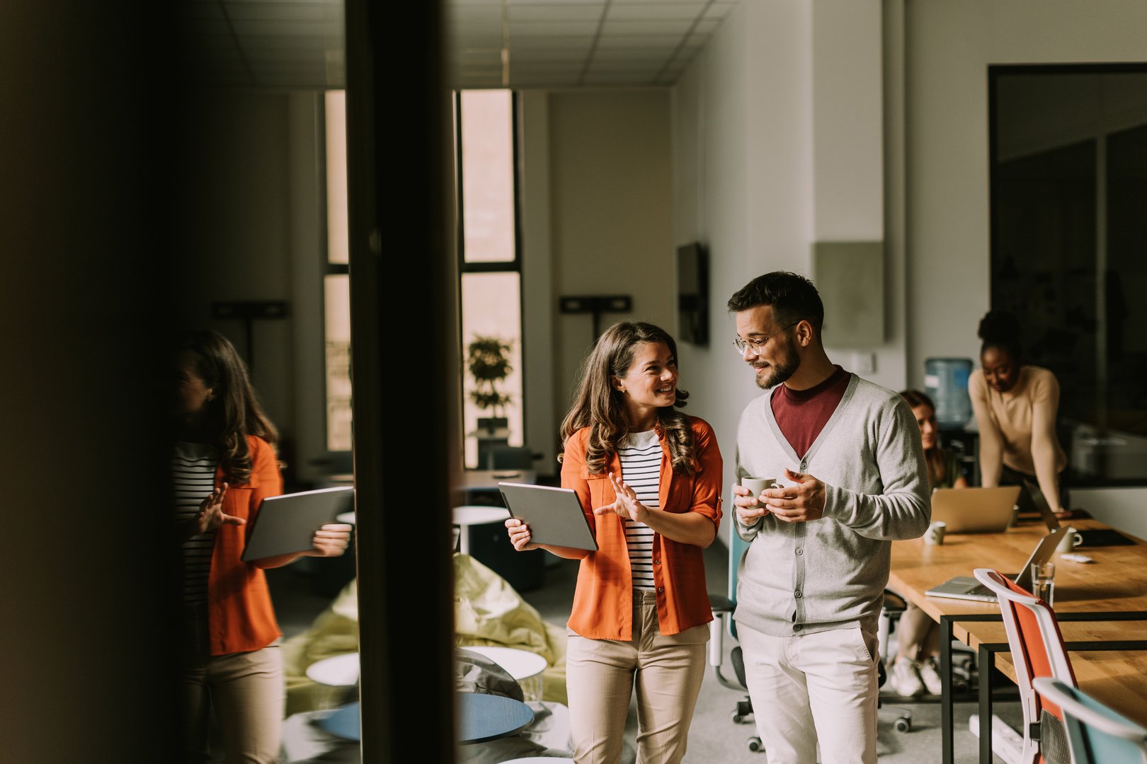 Young business couple standing with digital tablet in front of her team at the modern office
