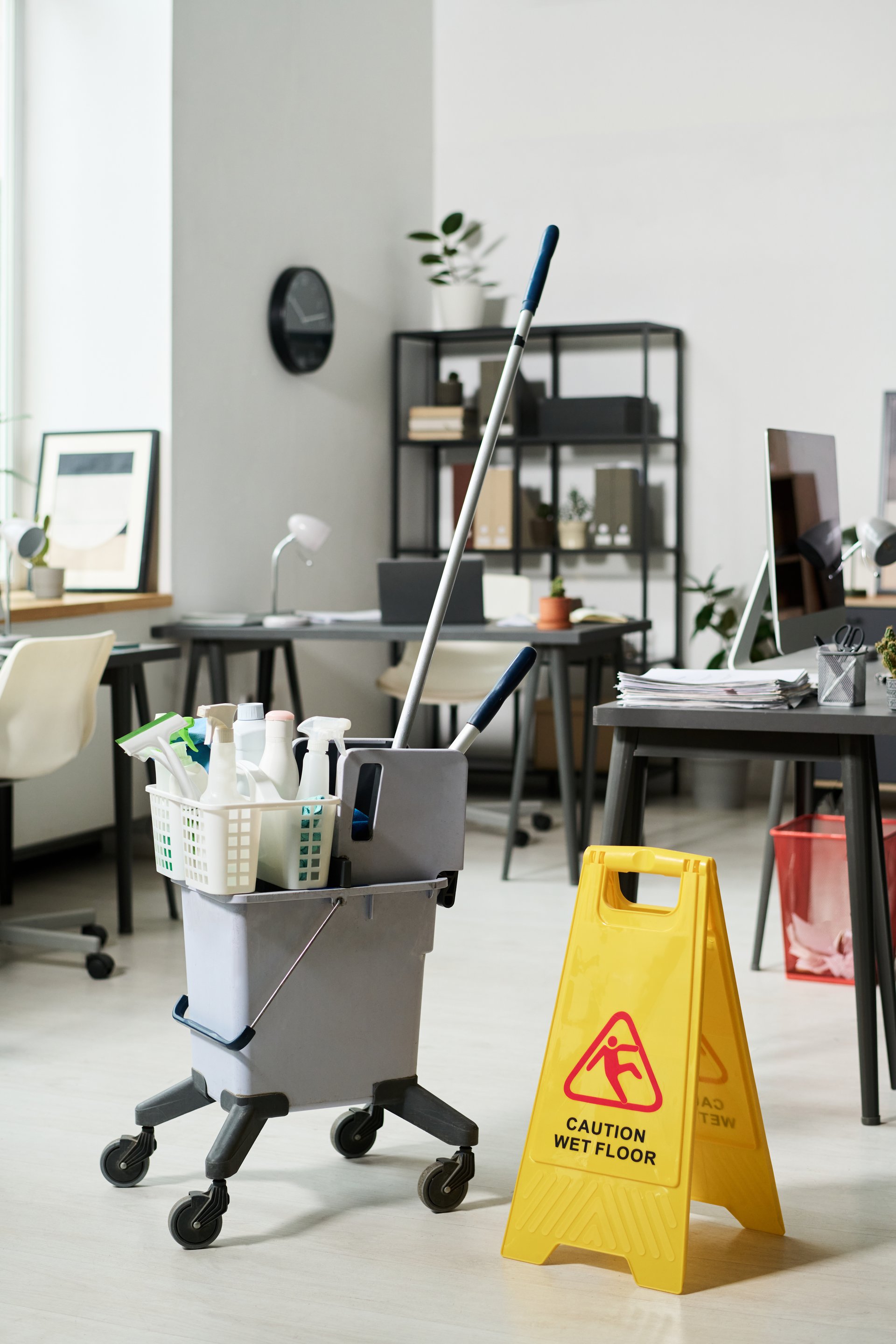 Bucket with detergents for cleaning office room with wet floor sign